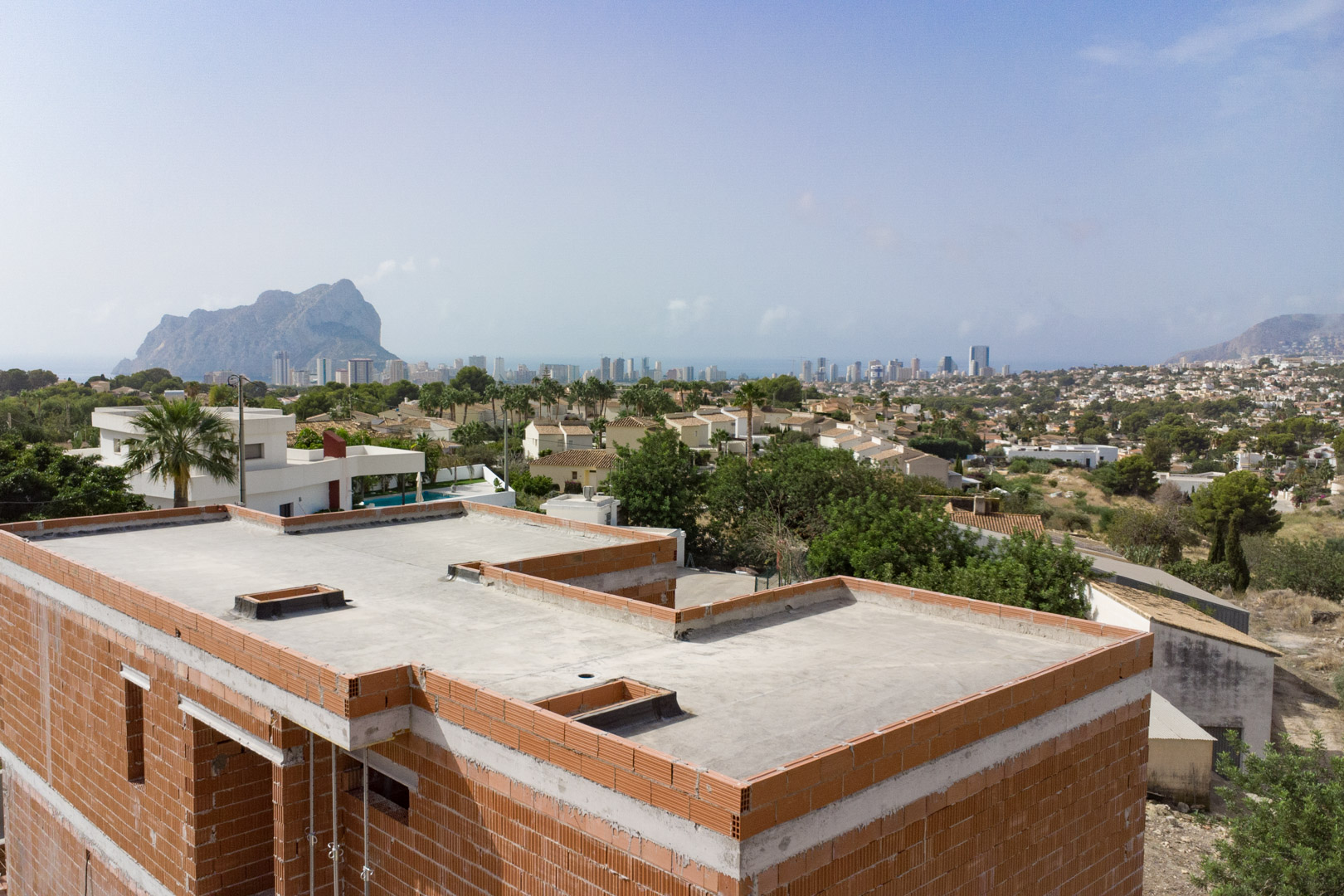 Vue panoramique depuis la structure en chantier sur la skyline de Calpe et le Peñón de Ifach, soulignant l'emplacement dominant du projet.
