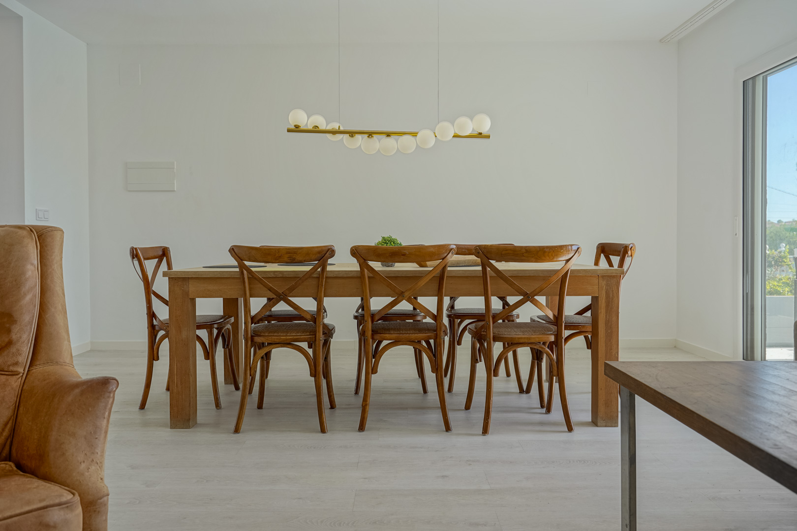 Espace salle à manger avec table en bois massif, chaises bistrot et luminaire suspendu moderne, le tout sur un sol en parquet clair.
