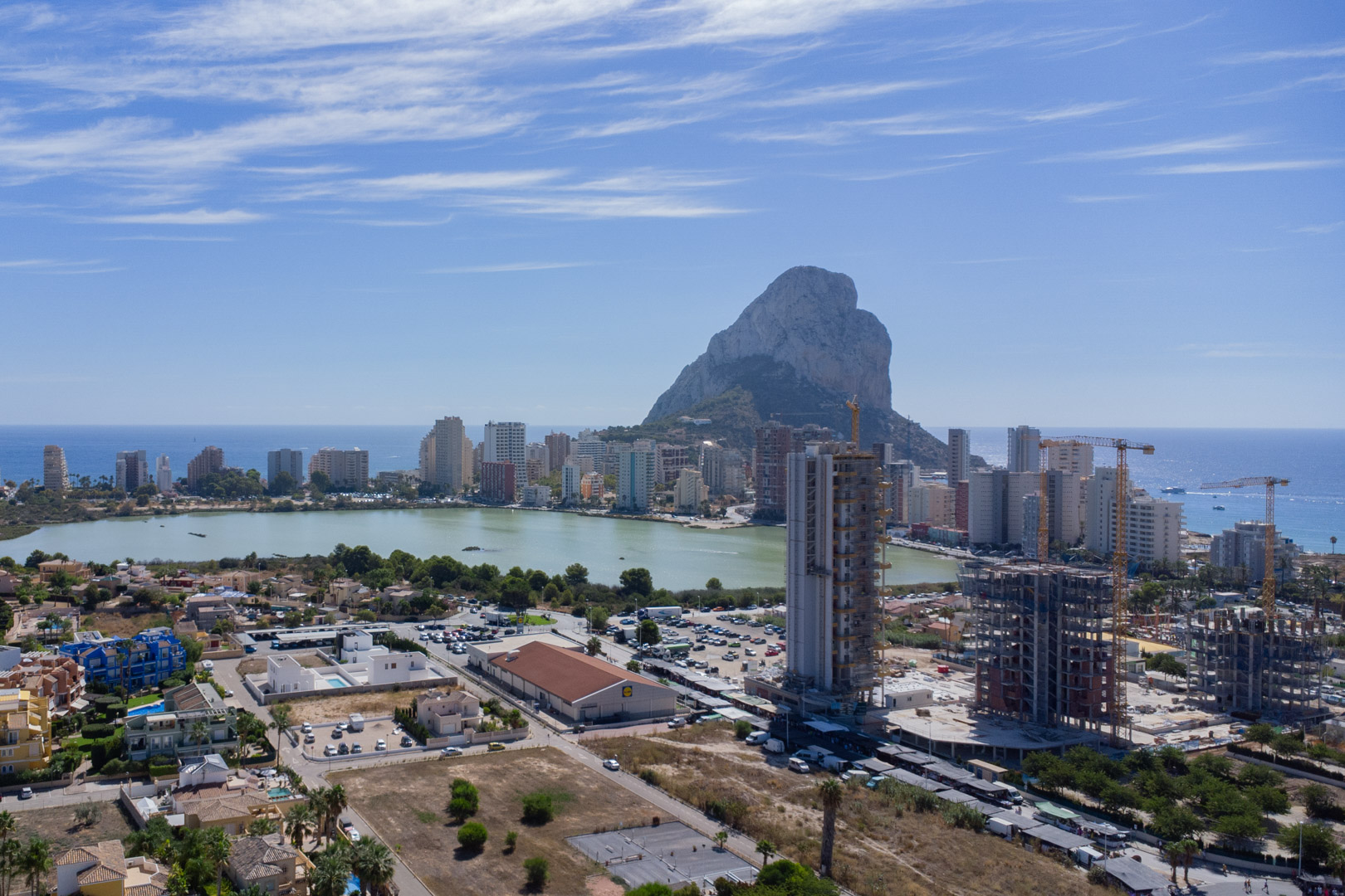 Vue panoramique surélevée de Calpe présentant le Peñón de Ifach, la lagune de Las Salinas et la silhouette urbaine côtière.