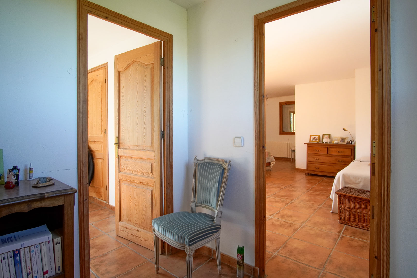 Dégagement avec sol en grès rustique et portes en bois massif, desservant des chambres lumineuses aux finitions traditionnelles et chaleureuses.