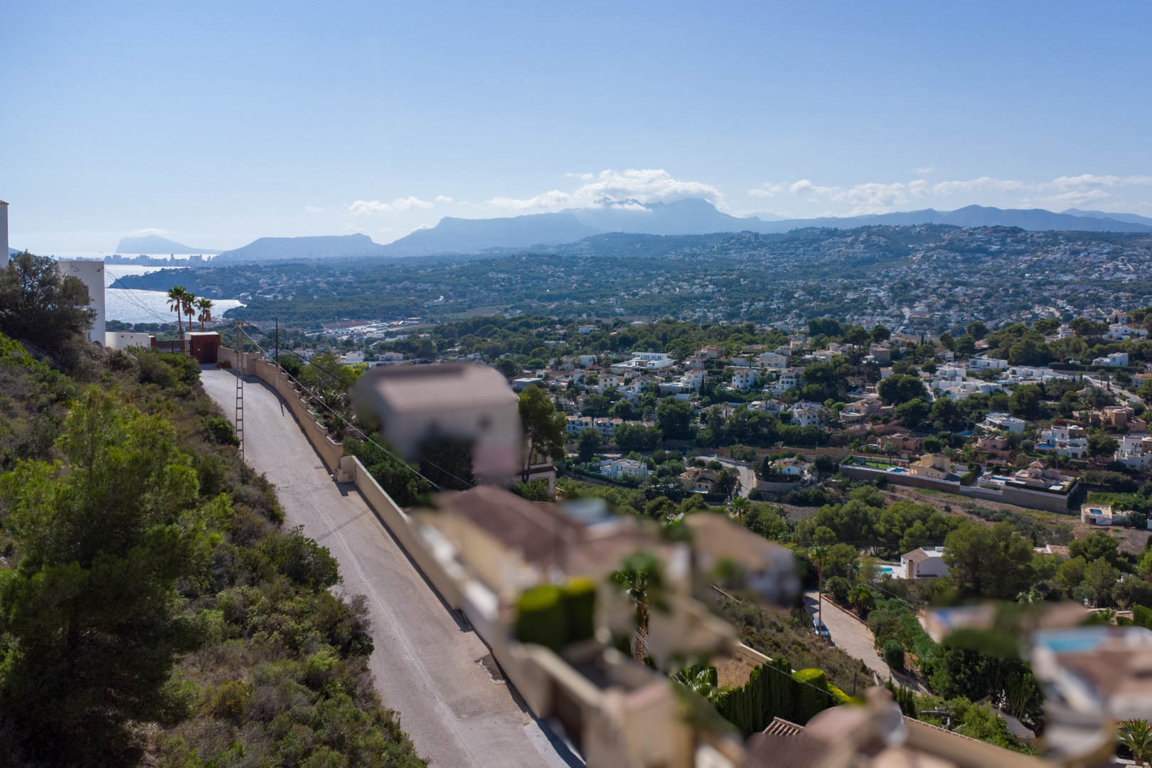 Vue panoramique depuis le terrain surélevé à El Portet, dominant la zone résidentielle, le littoral de Moraira et les chaînes de montagnes lointaines.