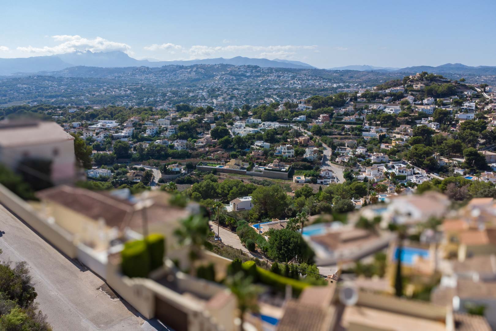 Vue panoramique surélevée du quartier résidentiel d'El Portet, illustrant la végétation méditerranéenne et les chaînes de montagnes à l'horizon.