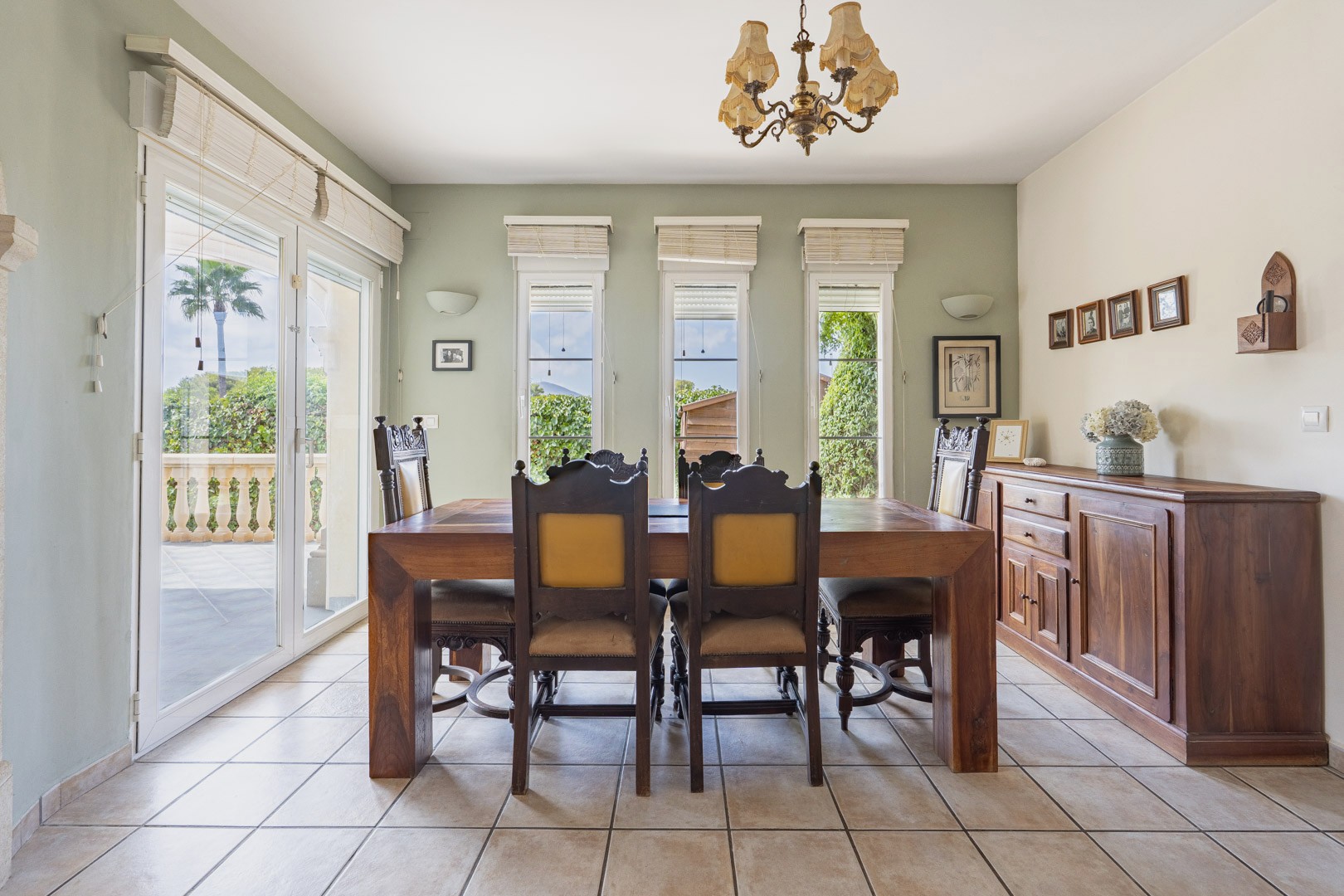 Salle à manger lumineuse avec table en bois massif, buffet assorti et accès à une terrasse extérieure.