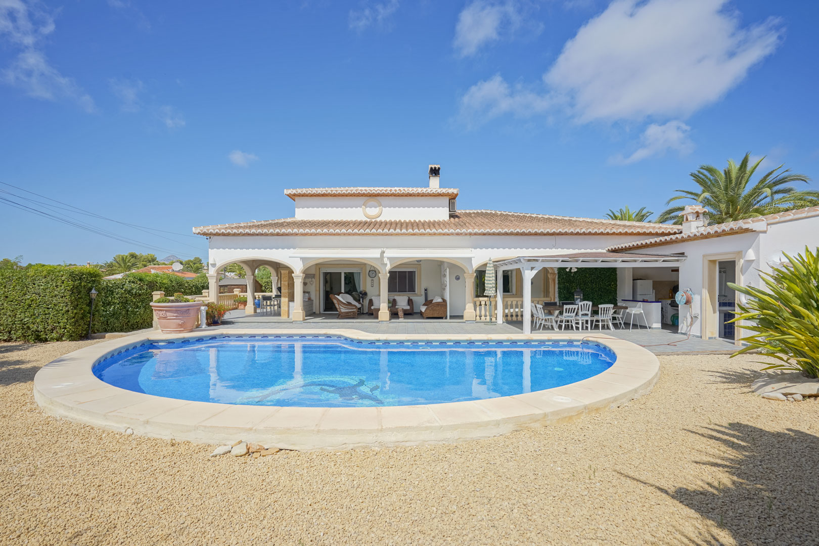 Vue sur la piscine carrelée et la terrasse couverte avec des arcades d'une villa à Jávea.
