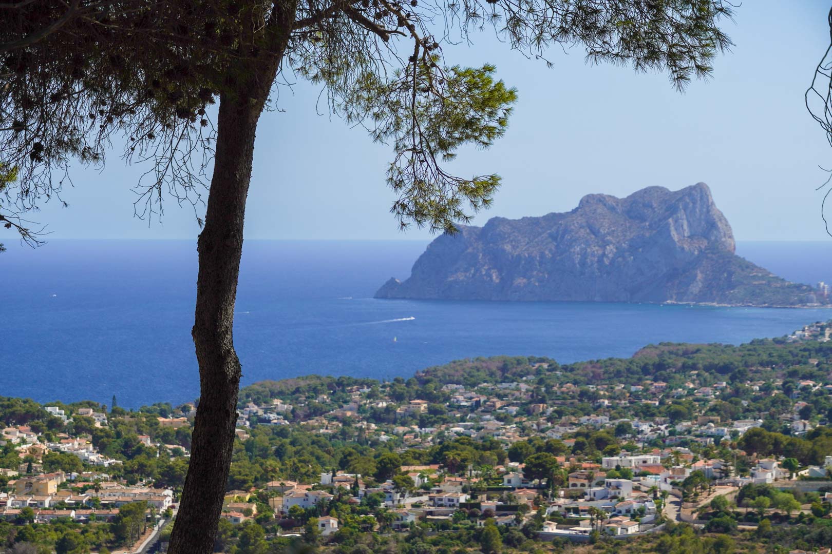 Vue panoramique depuis la propriété sur la mer Méditerranée, avec le Peñón de Ifach à l'horizon et le paysage de Moraira encadré par des pins indigènes.