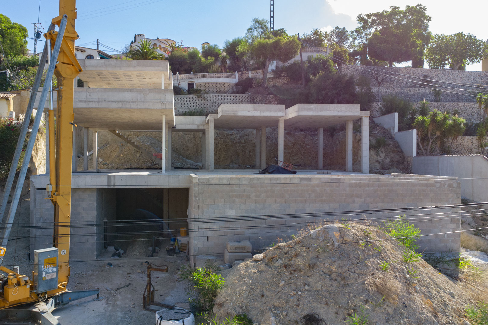 Vue de la structure en béton armé en cours de construction à San Jaime, illustrant les trois niveaux de la villa et l'espace garage sur un terrain escarpé.