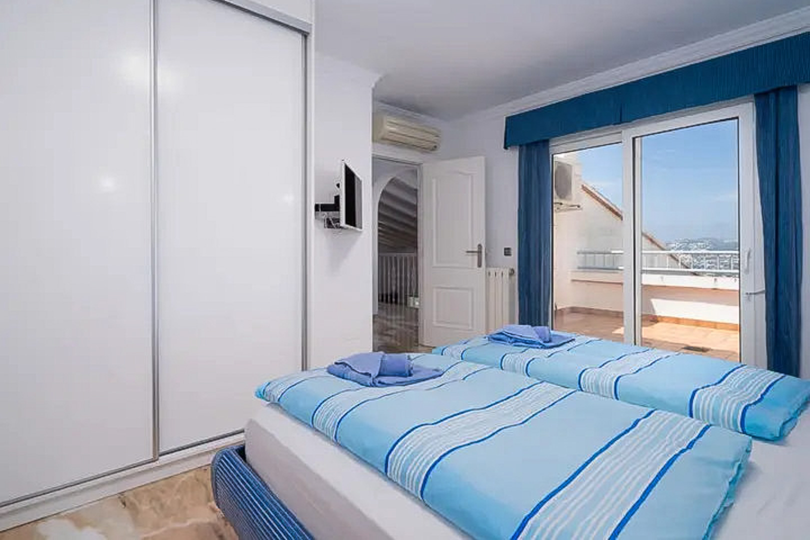 Chambre avec deux lits simples, grand placard à portes coulissantes et accès à une terrasse privée. Comprend la climatisation, une télévision murale et un sol en carrelage.