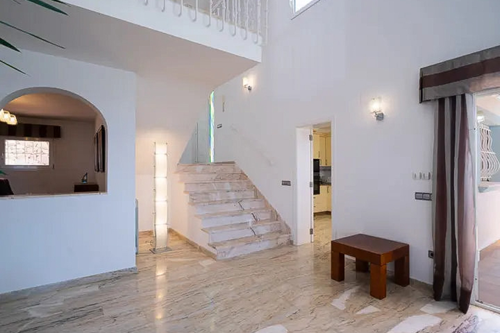 Hall d'entrée avec sols en marbre poli, escalier élégant et plafonds à double hauteur offrant une luminosité naturelle et une sensation d'espace.
