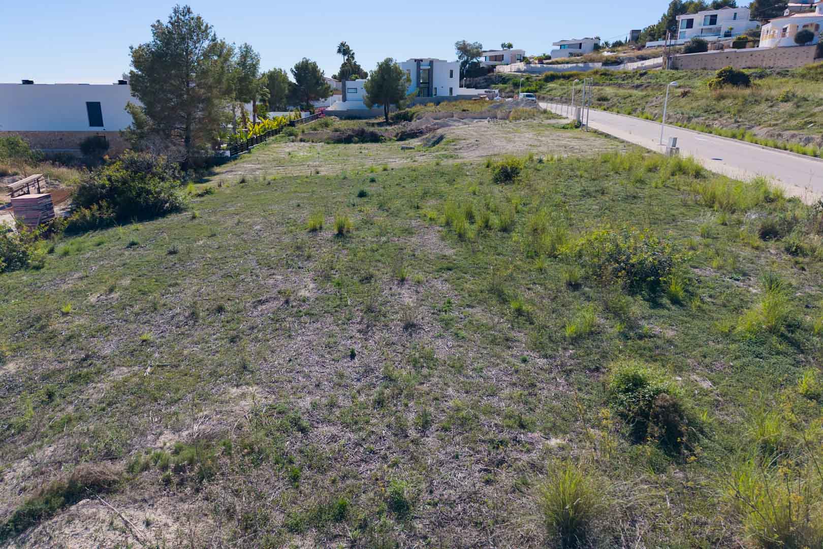 Terrain urbain plat à El Tesoro, Moraira, avec accès par route asphaltée et entouré de villas modernes. Il offre des vues dégagées sur la vallée environnante.