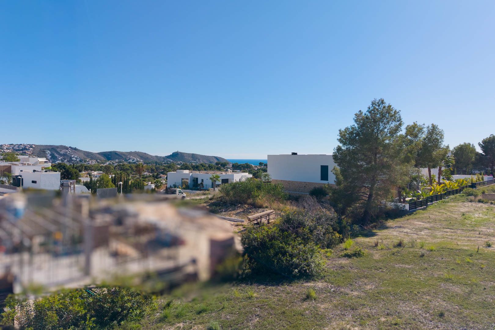 Vue panoramique depuis le terrain urbain à El Tesoro, illustrant le relief plat, les villas modernes voisines et une vue dégagée sur la vallée et la mer Méditerranée.