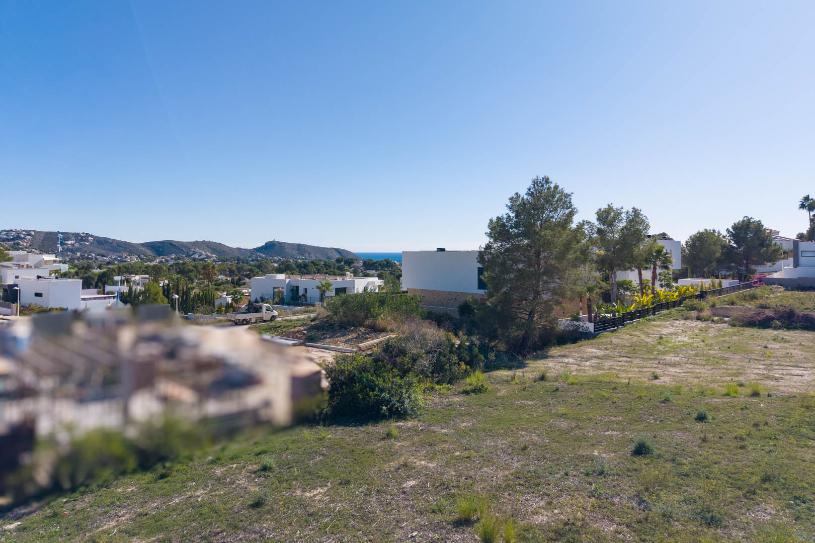 Vue panoramique depuis le terrain urbain d'El Tesoro, montrant le relief plat, les villas modernes environnantes et une vue dégagée sur la vallée et la mer.