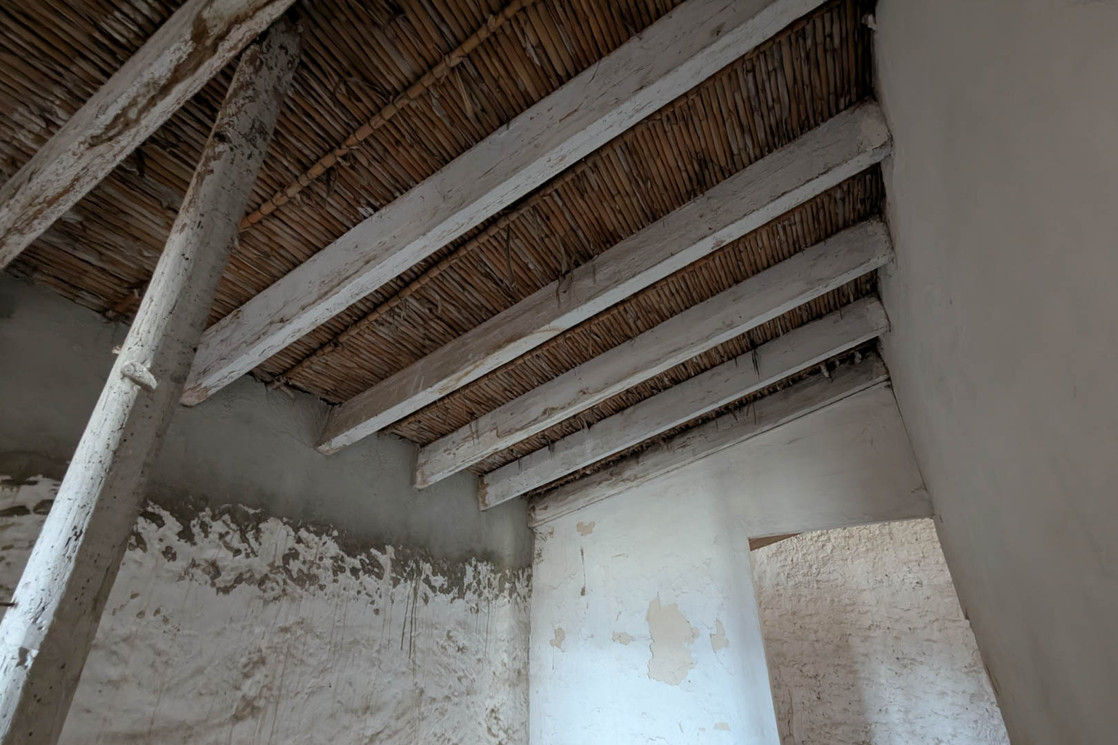 Vue intérieure montrant le plafond d'origine en canisse et poutres en bois blanchies à la chaux. Les murs en pierre naturelle conservent leur enduit traditionnel.