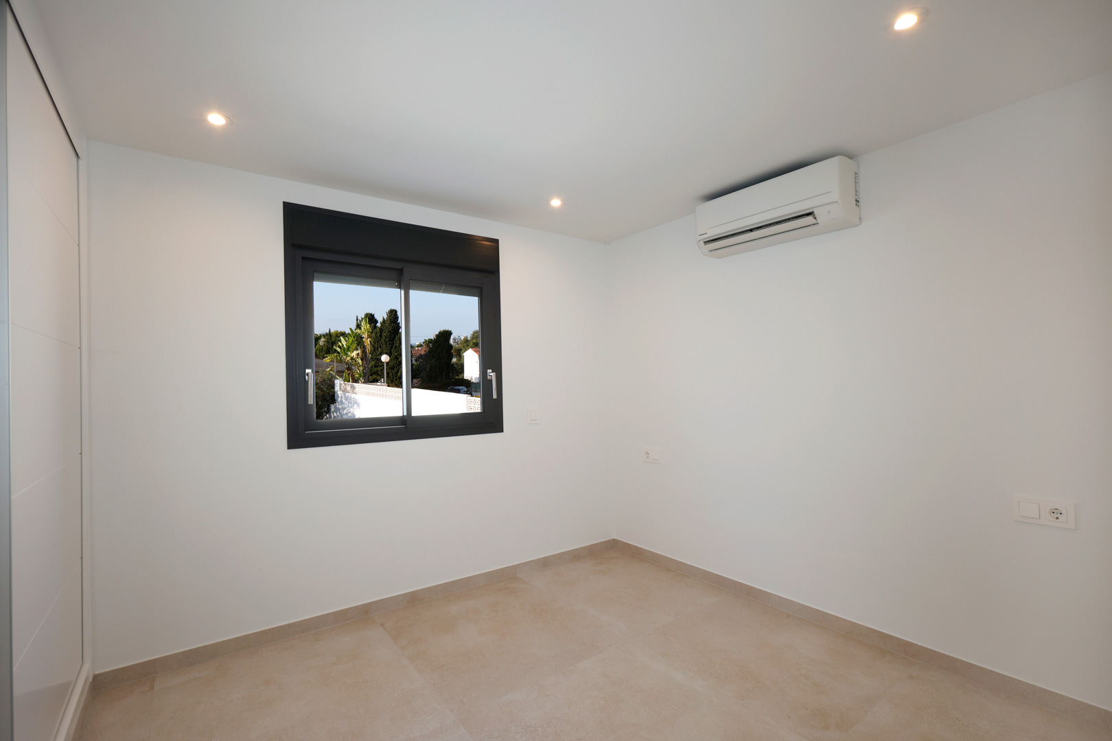 Chambre lumineuse avec sol en grès cérame, éclairage LED encastré, climatisation réversible et fenêtre en aluminium Technal.