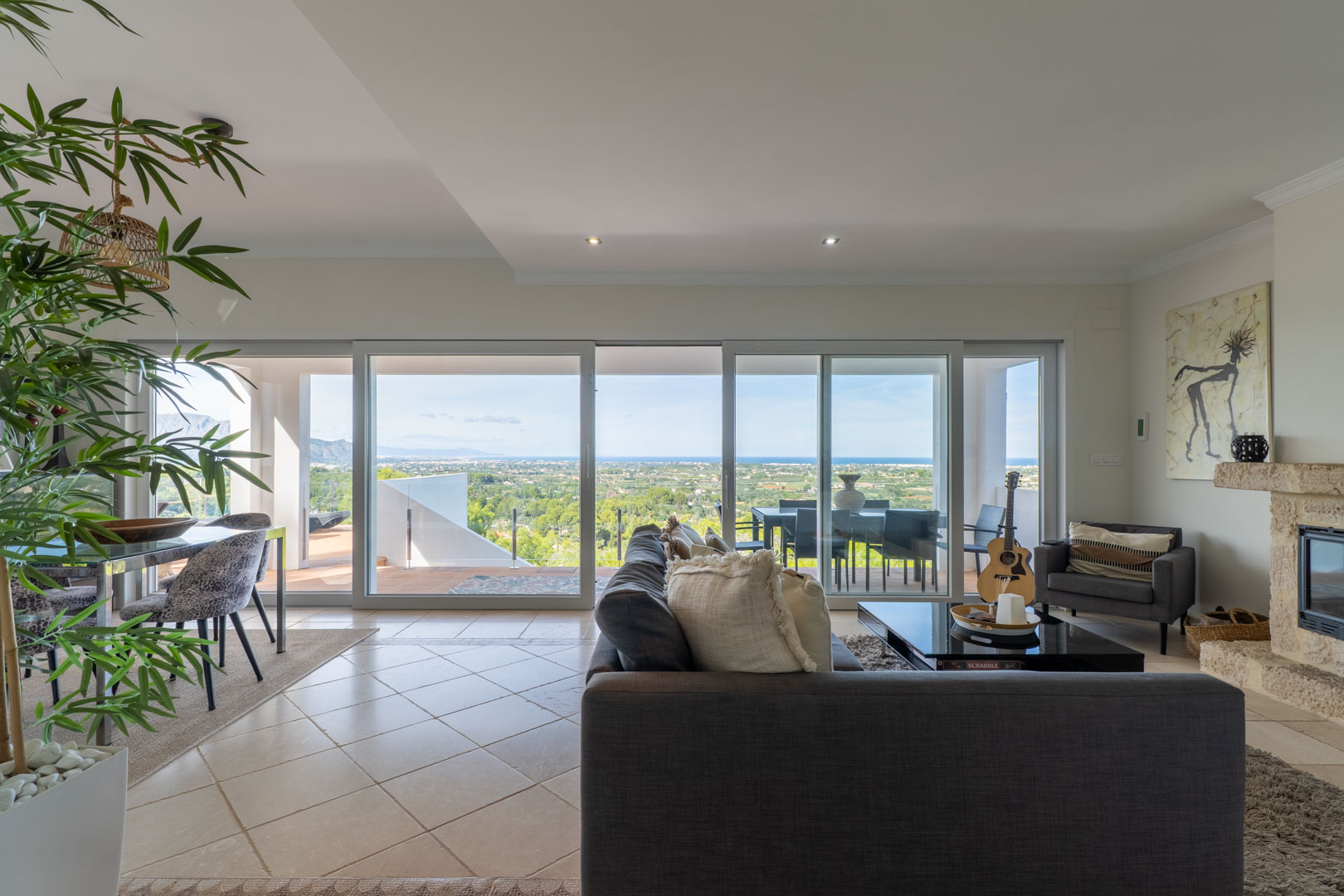 Espace de vie lumineux avec de grandes baies vitrées offrant une vue panoramique sur la mer, une cheminée en pierre naturelle et un accès direct à la terrasse.