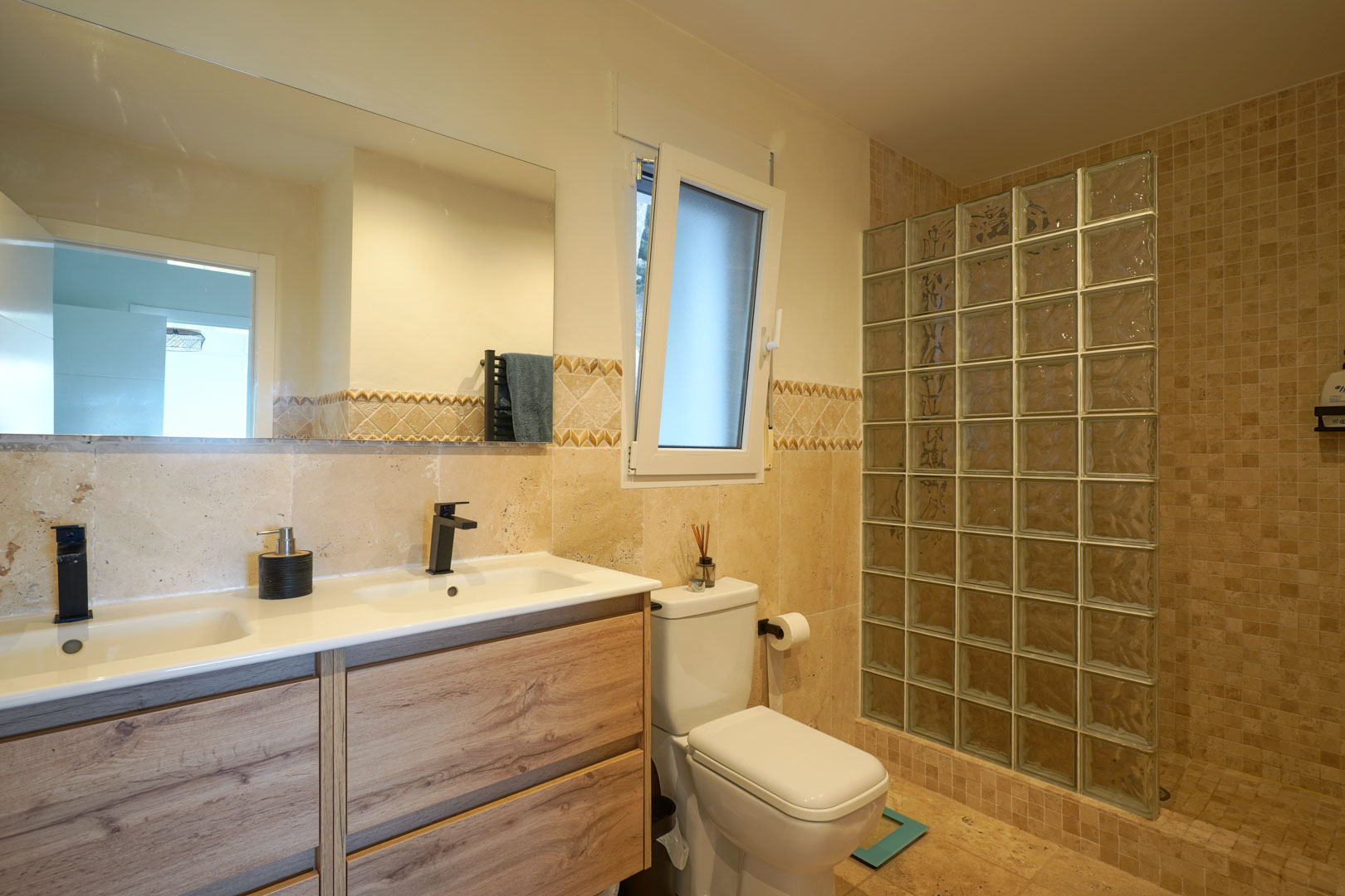 Salle de bain moderne avec double vasque en bois, robinetterie noire et douche à l'italienne avec paroi en briques de verre.