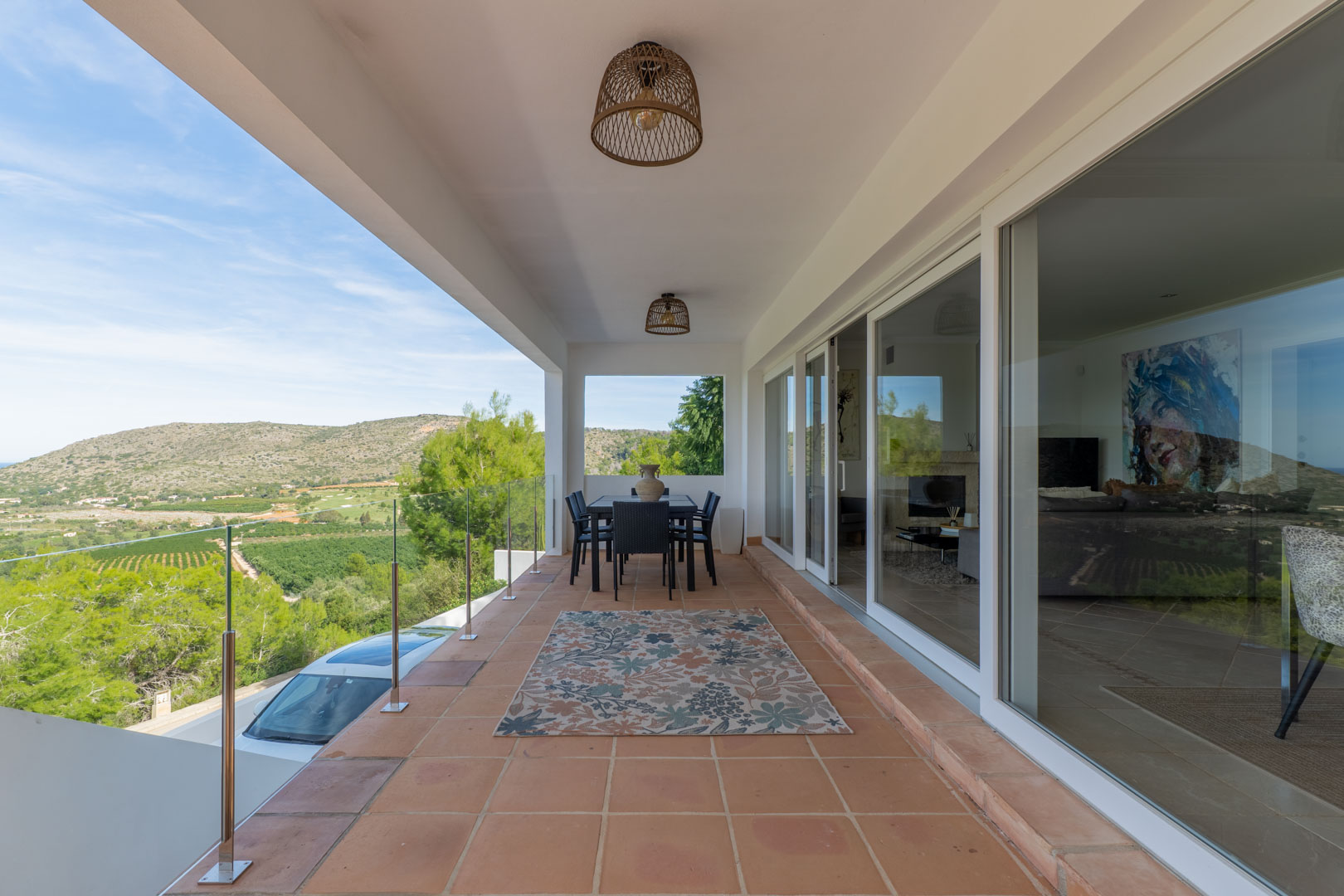 Terrasse couverte avec sol en terre cuite, garde-corps en verre et vue panoramique sur le golf. Comprend un coin repas extérieur et de larges baies vitrées coulissantes.