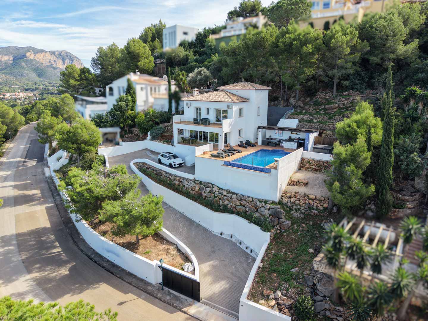 Vue aérienne de la villa méditerranéenne avec piscine privée, terrasses à plusieurs niveaux et cuisine d'été, nichée sur un terrain en pente avec murs en pierre.