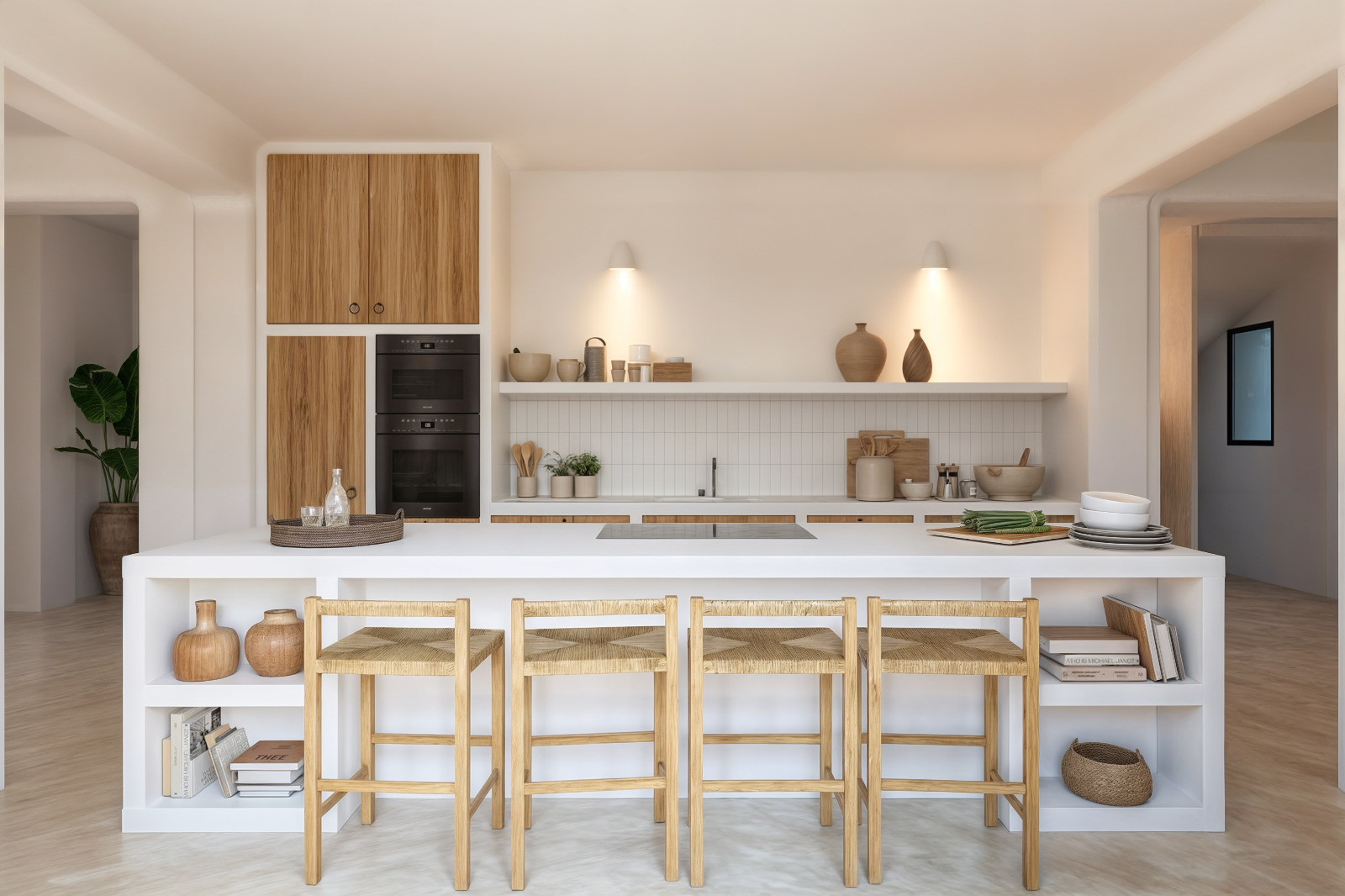 Cuisine de style ibizien avec îlot central blanc, tabourets en bois et fibres naturelles, fours encastrés et étagères ouvertes sous un éclairage tamisé.