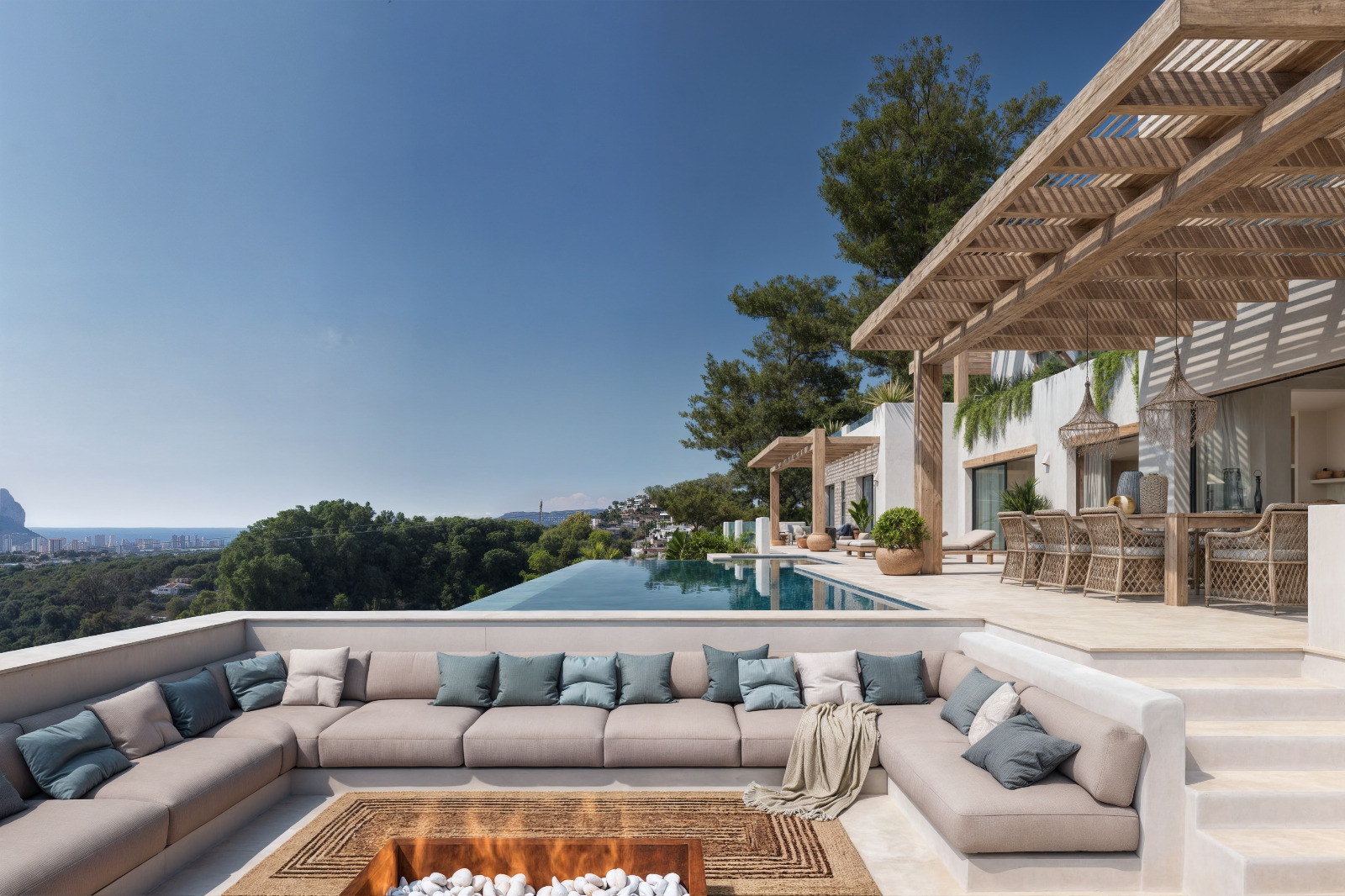 Espace lounge extérieur encastré avec brasero, terrasse sous pergola en bois et piscine à débordement offrant une vue panoramique sur la mer Méditerranée.