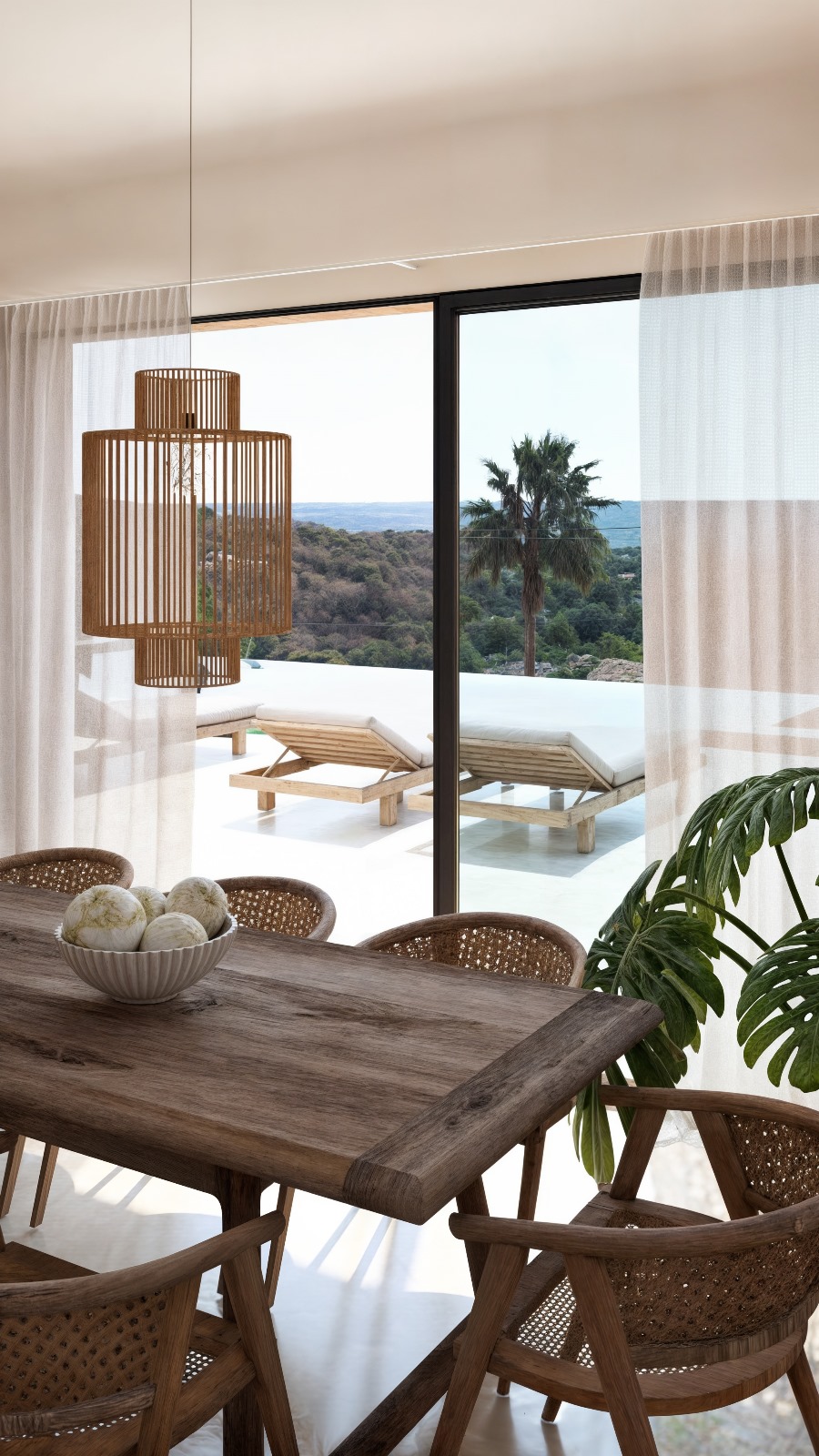 Espace salle à manger avec table en bois massif et suspension en bois, offrant une vue sur la terrasse, la piscine à débordement et la mer par de grandes baies vitrées.