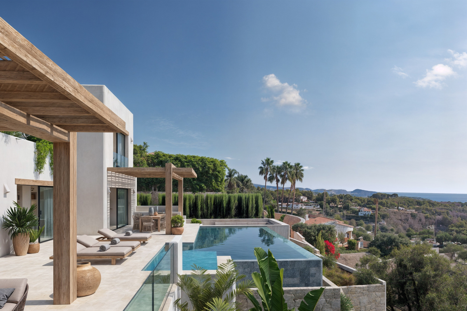 Terrasse extérieure avec piscine à débordement, pergolas en bois et vue panoramique sur la mer. La façade blanche de style ibizien s'intègre à la végétation méditerranéenne.