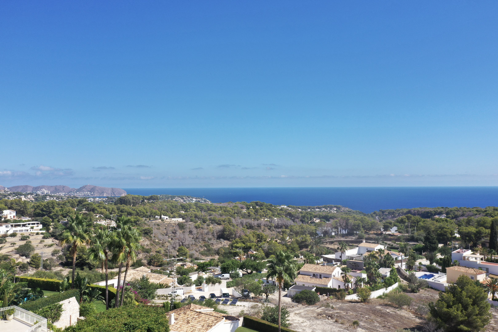 Vue panoramique depuis Racó de Galeno vers la mer Méditerranée, mettant en valeur la végétation côtière et les villas résidentielles de Benissa sous un ciel dégagé.