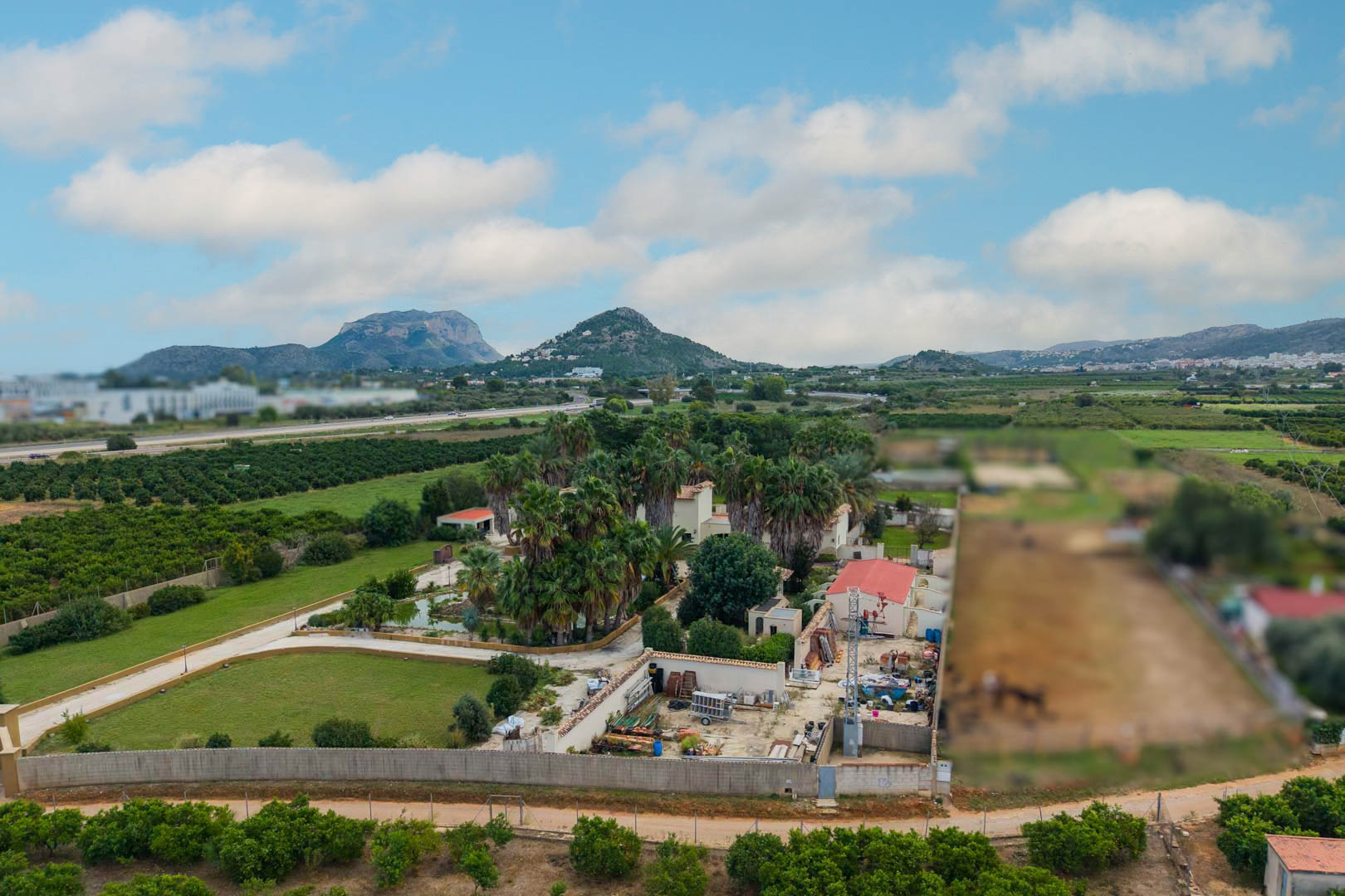 Vue aérienne du domaine de 10 000 m2 à Ondara, illustrant les jardins de palmiers, l'étang central et le panorama sur les montagnes environnantes.
