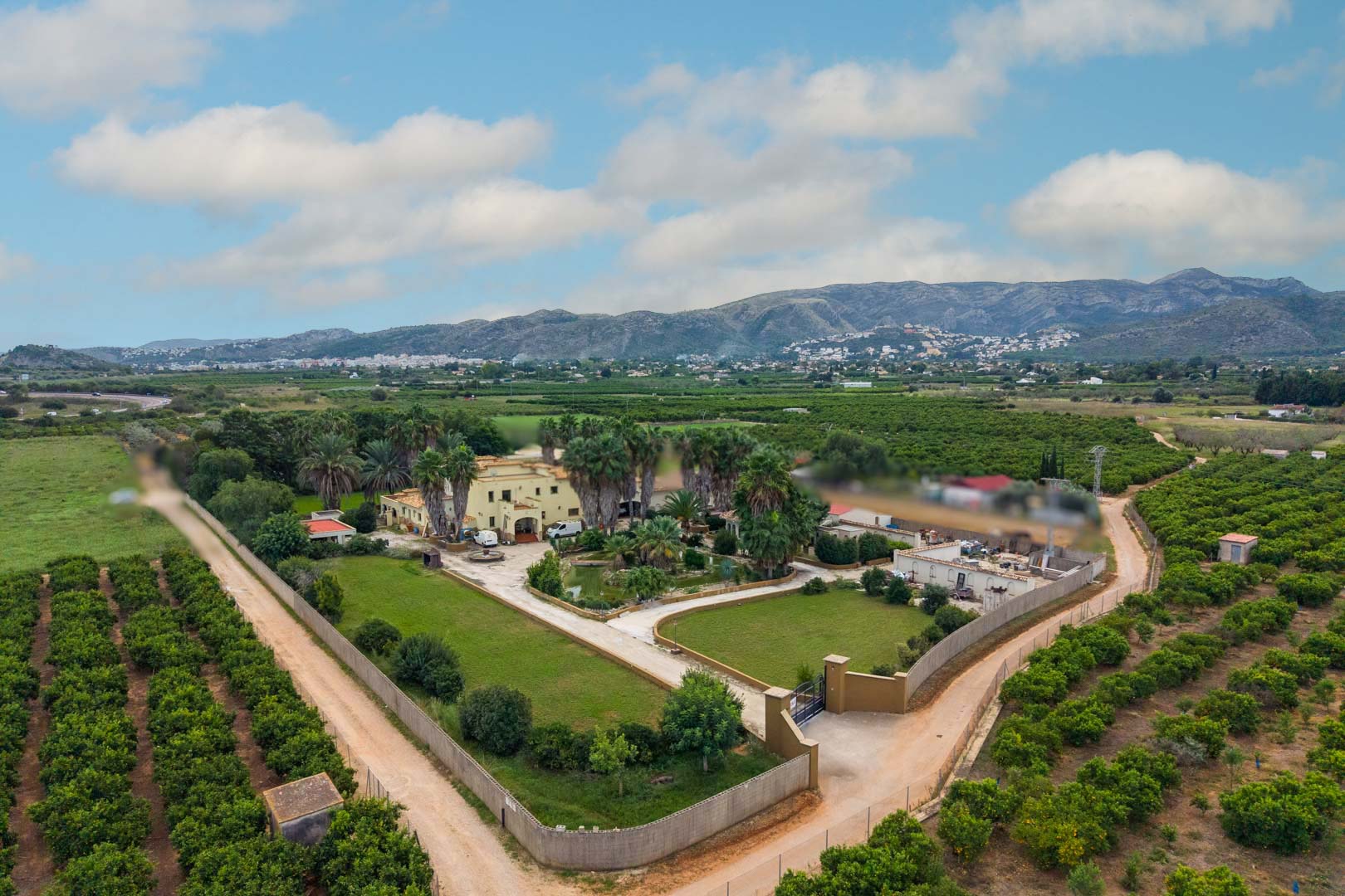 Vue aérienne du domaine de 10 000 m² illustrant la maison principale, l'étang central et les jardins paysagers entourés de vergers d'agrumes et de montagnes.