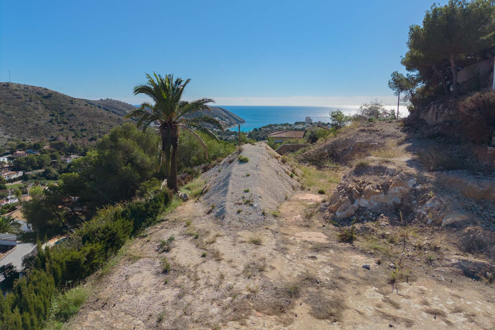 Vue panoramique depuis le terrain surélevé surplombant la baie d'El Portet, mettant en valeur le paysage méditerranéen et la vue dégagée sur la mer à Moraira.
