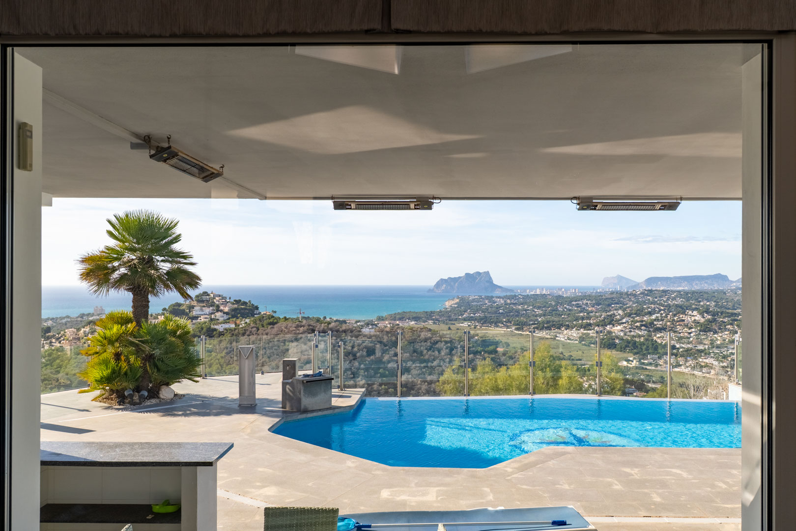 Vue de l'intérieur sur la piscine privée avec vue sur la mer et le paysage de Moraira.