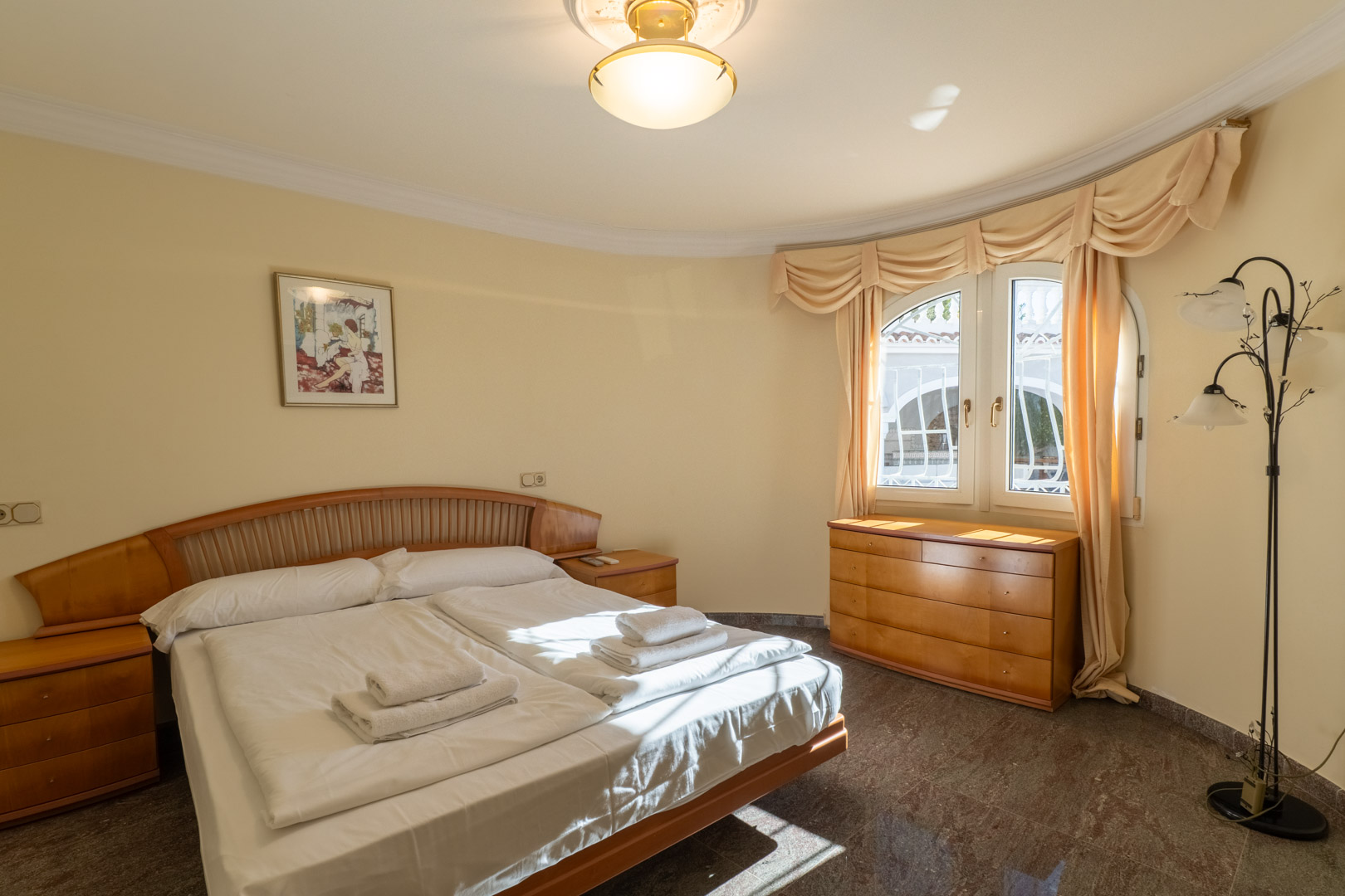 Chambre avec mobilier en bois intégré, sol en granit et une fenêtre en arc apportant une lumière naturelle sur les murs incurvés.