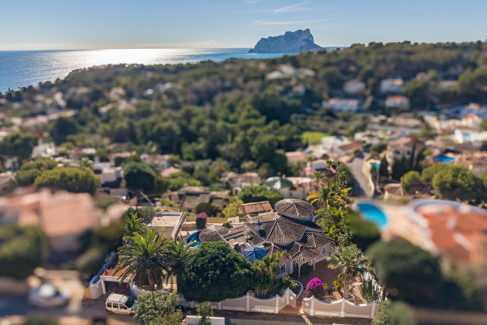 Vue aérienne de la villa à Benissa, révélant ses toits en tuiles et son jardin arboré avec une vue dégagée sur la mer Méditerranée et le Peñón de Ifach.