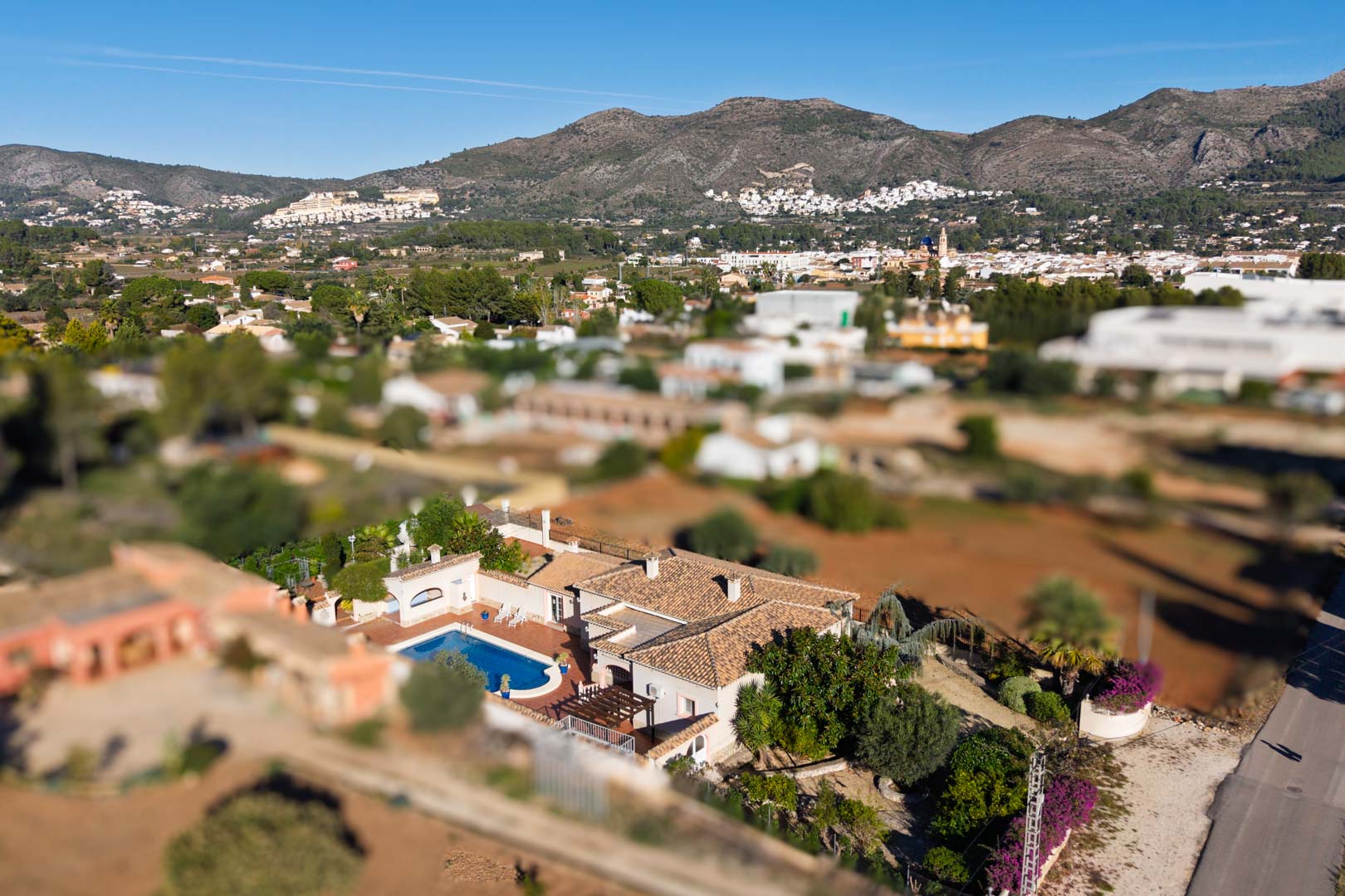 Vue aérienne de la villa méditerranéenne avec sa piscine, sa toiture en tuiles et un panorama dégagé sur le village de Jalón et les montagnes.