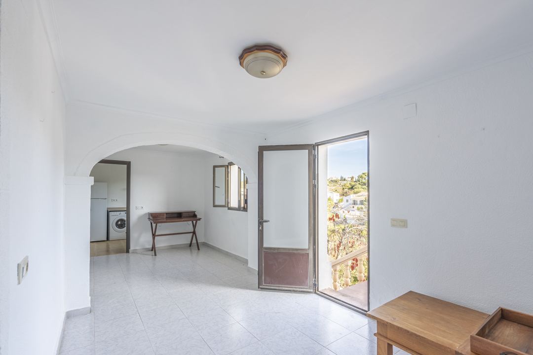 Espace de vie lumineux avec sol en grès cérame, arche décorative et accès direct à une terrasse extérieure offrant une vue dégagée.