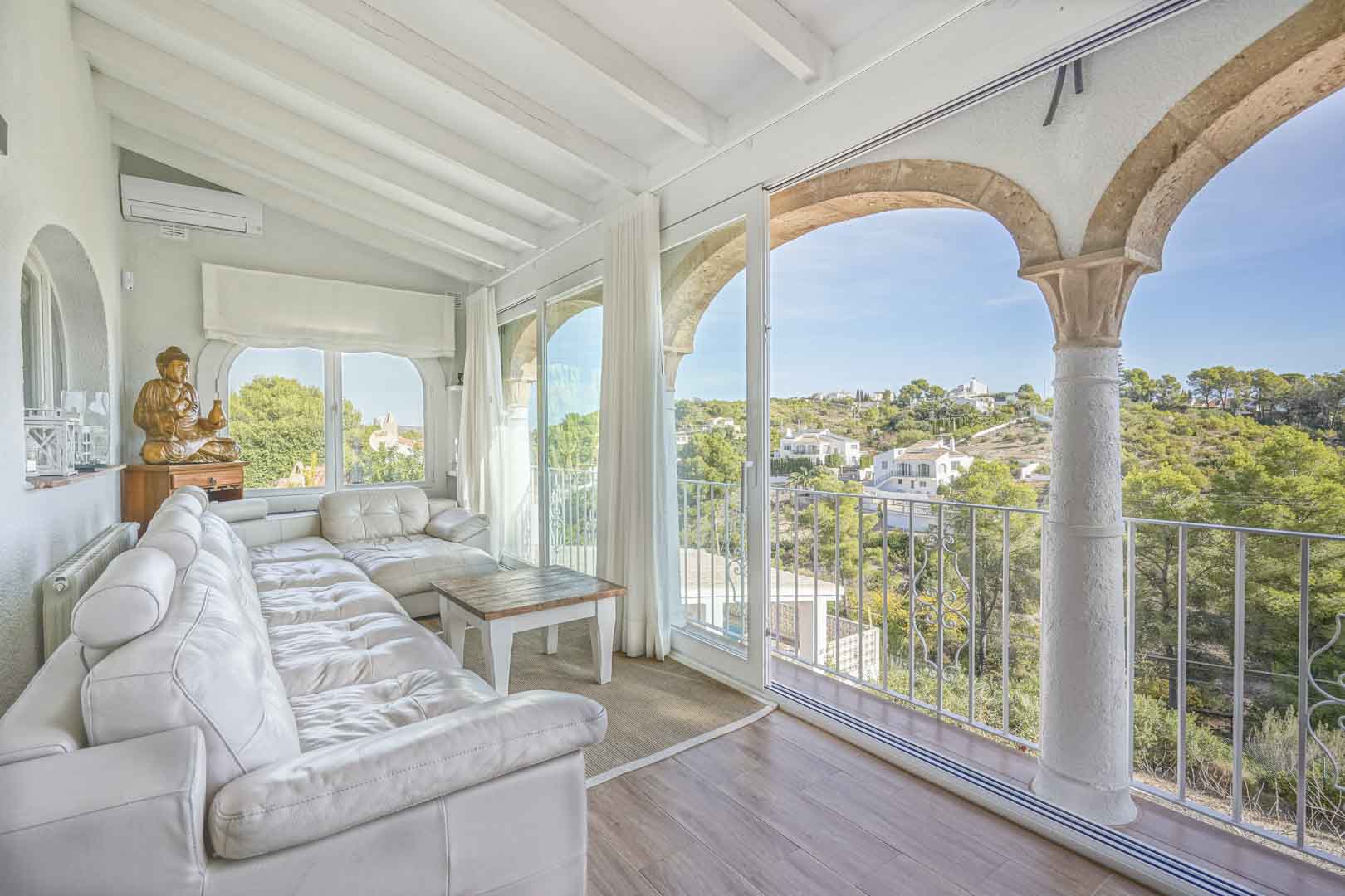 Naya vitrée avec arches en pierre de Tosca, plafond à poutres blanches et vue dégagée sur la vallée. Équipée d'un canapé en cuir et d'un système de climatisation.