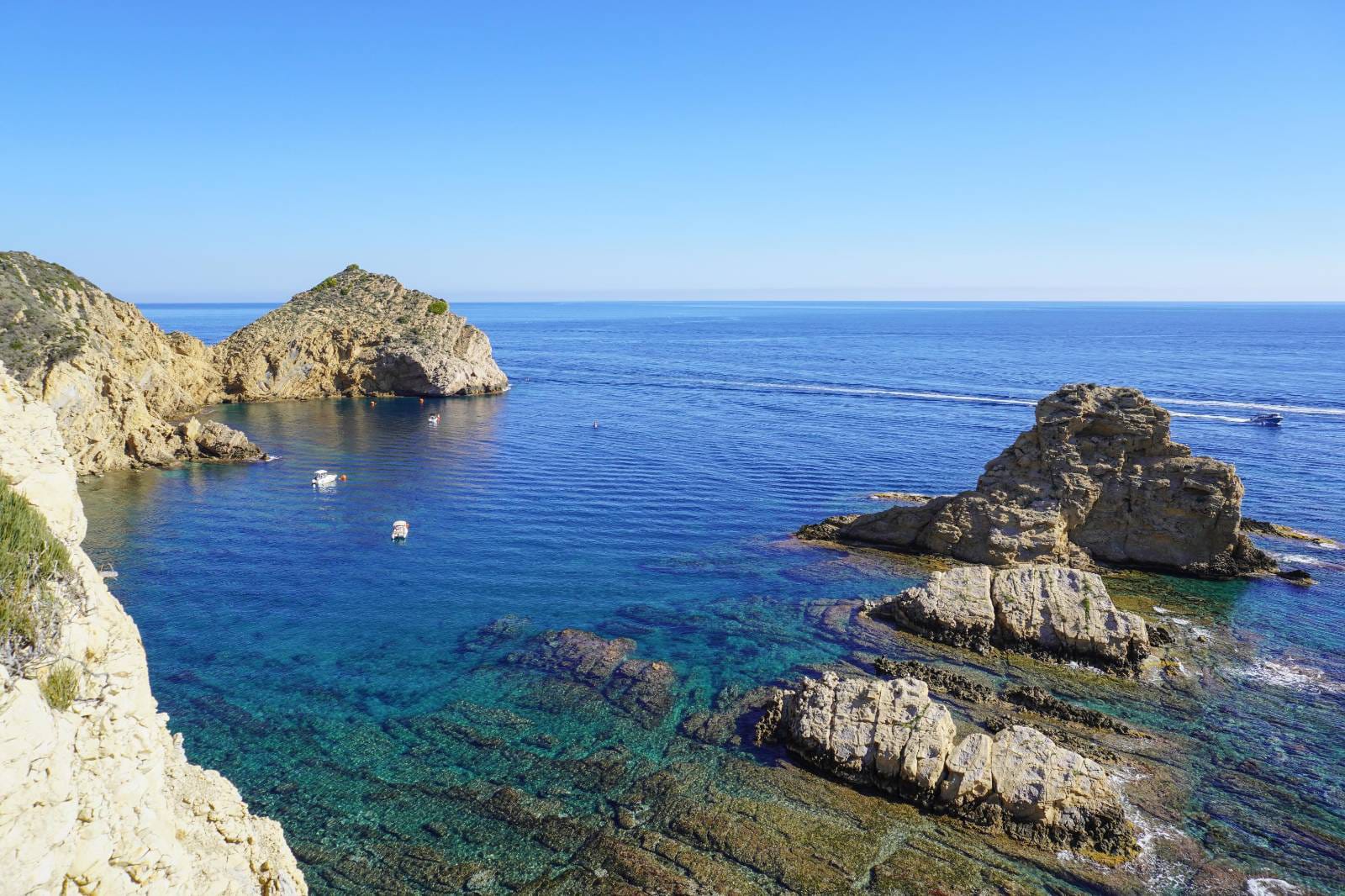 Vue panoramique d'une crique aux eaux turquoise et falaises rocheuses à Jávea, illustrant le cadre côtier à proximité de la villa.