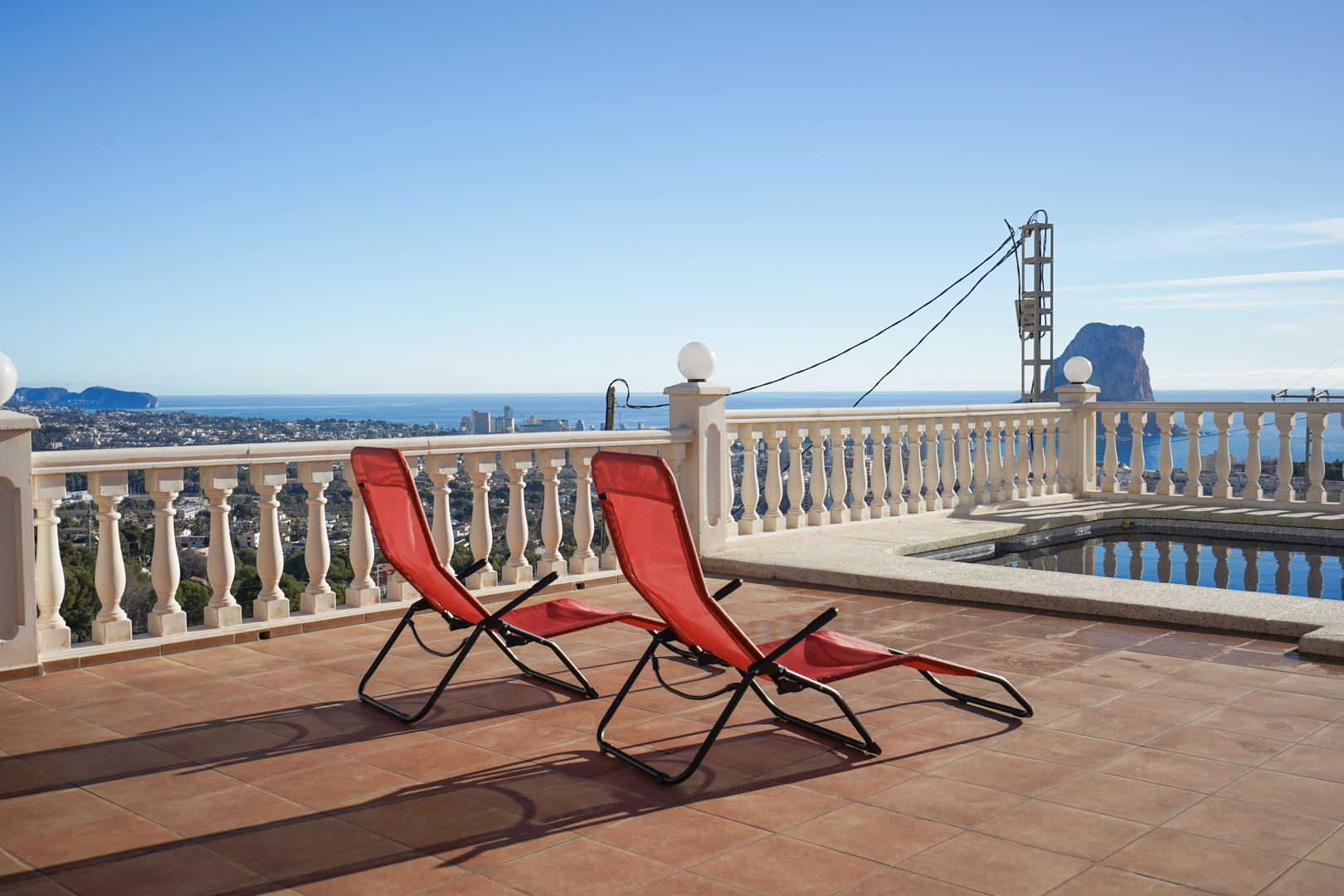 Terrasse surélevée avec carrelage en terre cuite, balustrade blanche et vue panoramique sur le Peñón de Ifach et la mer Méditerranée.