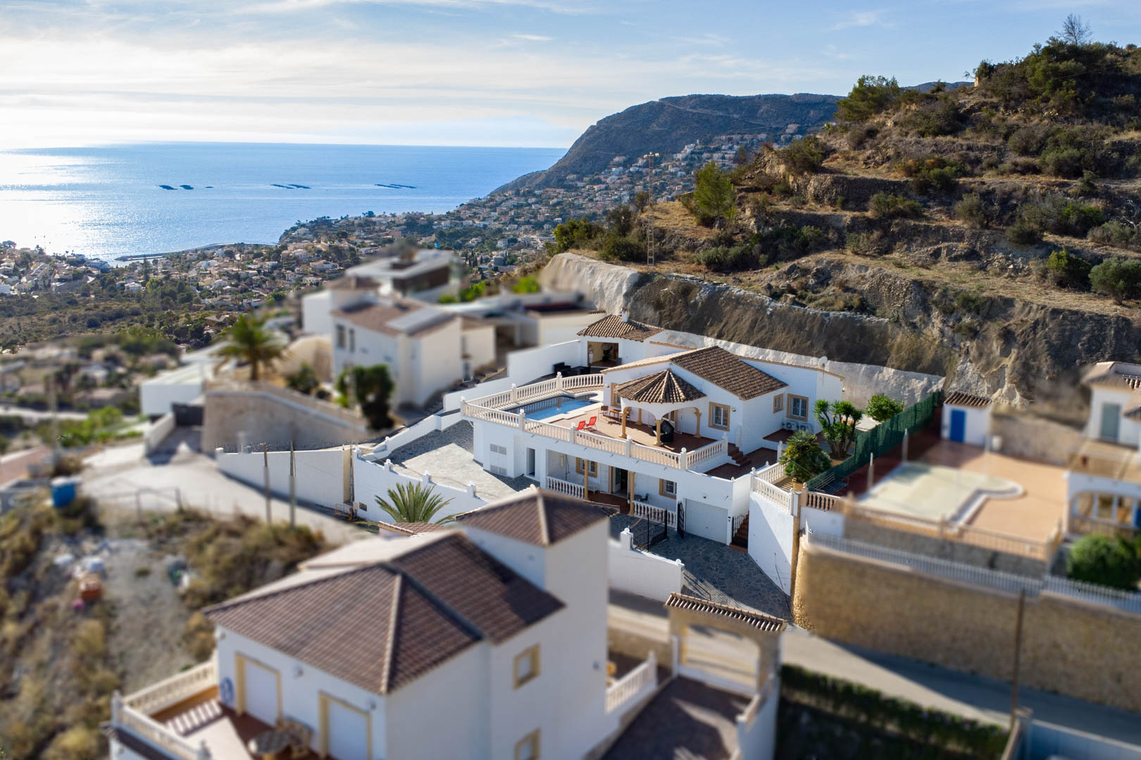 Vue aérienne de la villa à Partida Cucarres, montrant la terrasse avec piscine, les toits en tuiles traditionnelles et la vue panoramique sur la côte méditerranéenne.