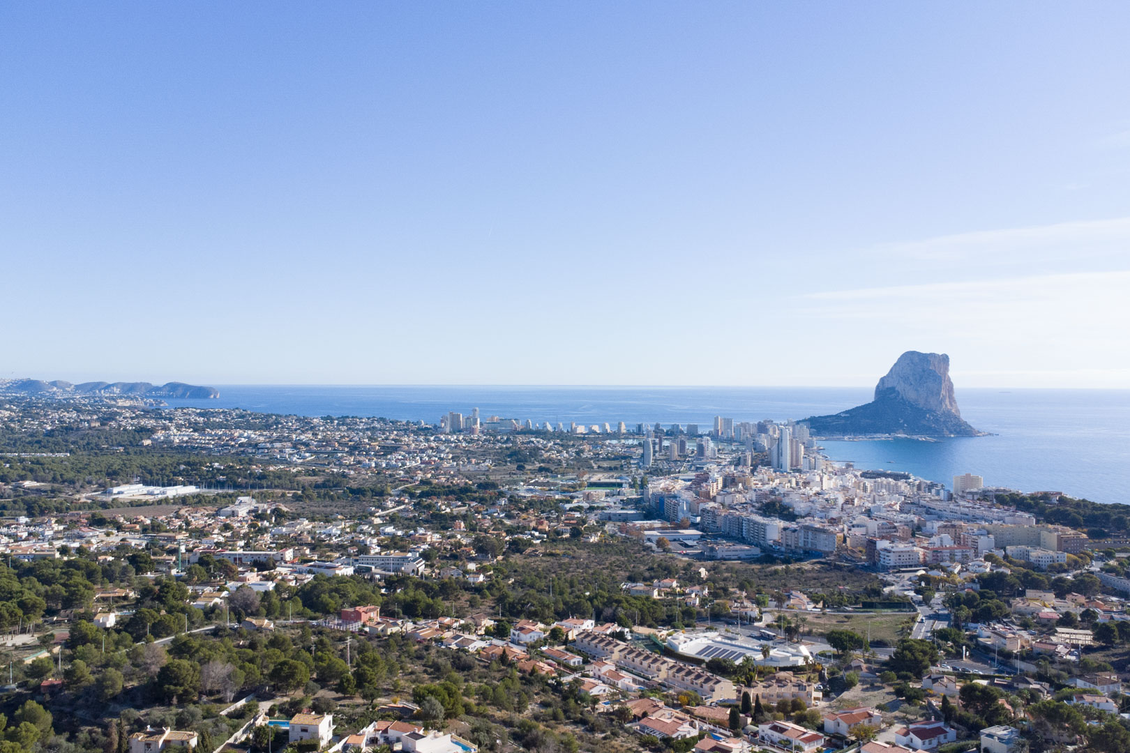 Vue aérienne panoramique de la côte de Calpe, mettant en évidence le Peñón de Ifach, la silhouette de la ville et l'étendue de la mer Méditerranée.