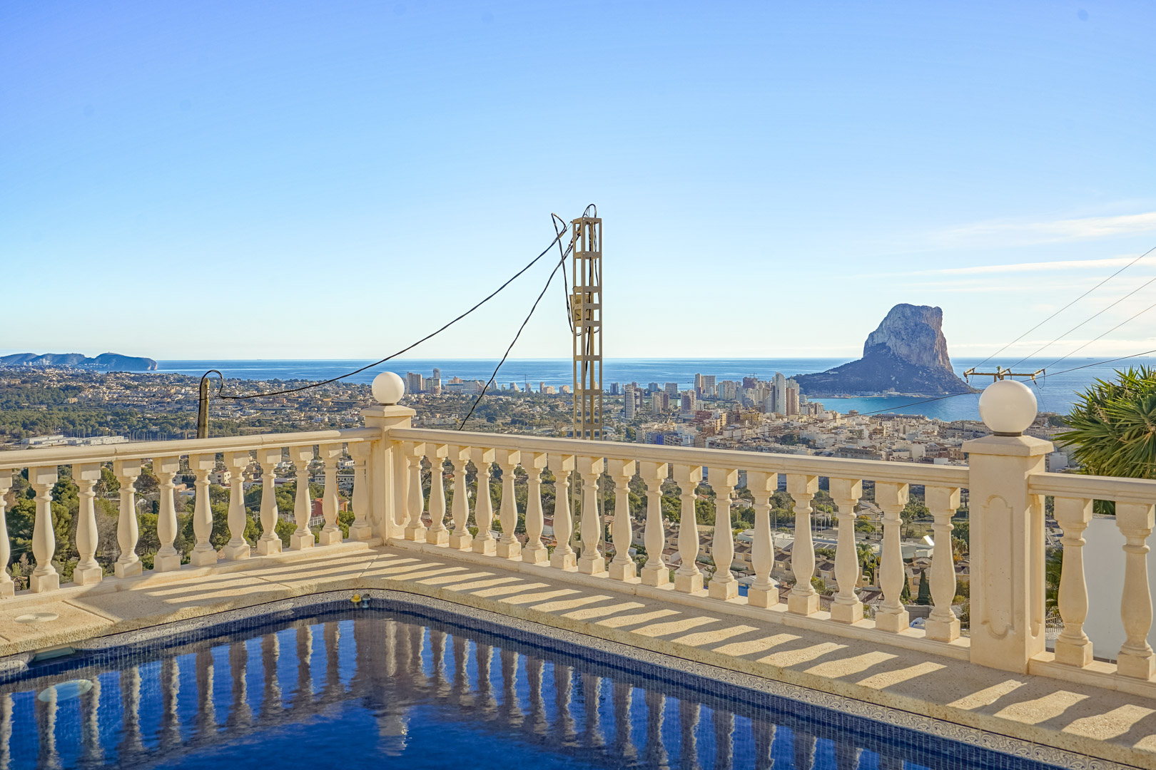 Vue depuis la piscine avec balustrade classique sur le Peñón de Ifach, la silhouette urbaine de Calpe et le littoral méditerranéen.