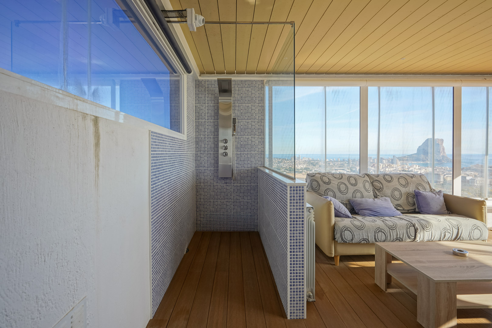 Espace bien-être à l'étage avec douche d'hydromassage en mosaïque bleue et salon vitré offrant une vue panoramique sur le Peñón de Ifach et Calpe.