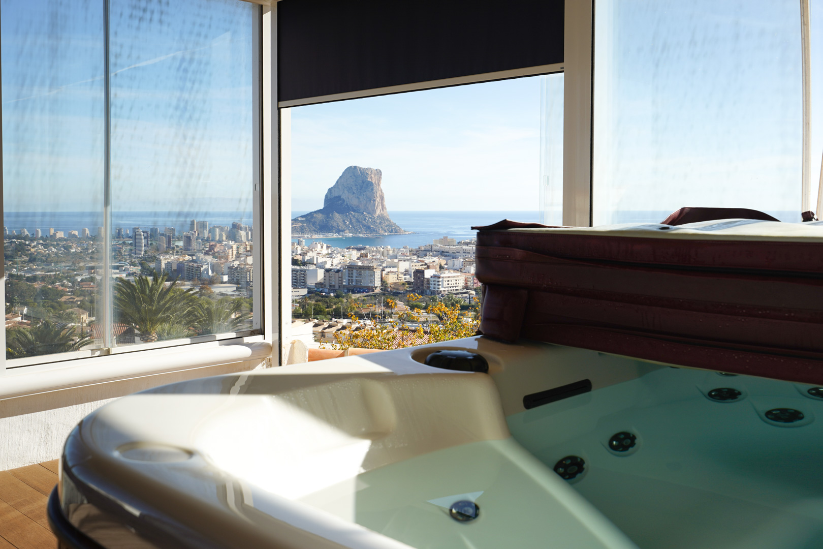 Espace jacuzzi à l'étage supérieur avec enceinte vitrée, offrant une vue panoramique sur le Peñón de Ifach, la ville de Calpe et la mer Méditerranée.