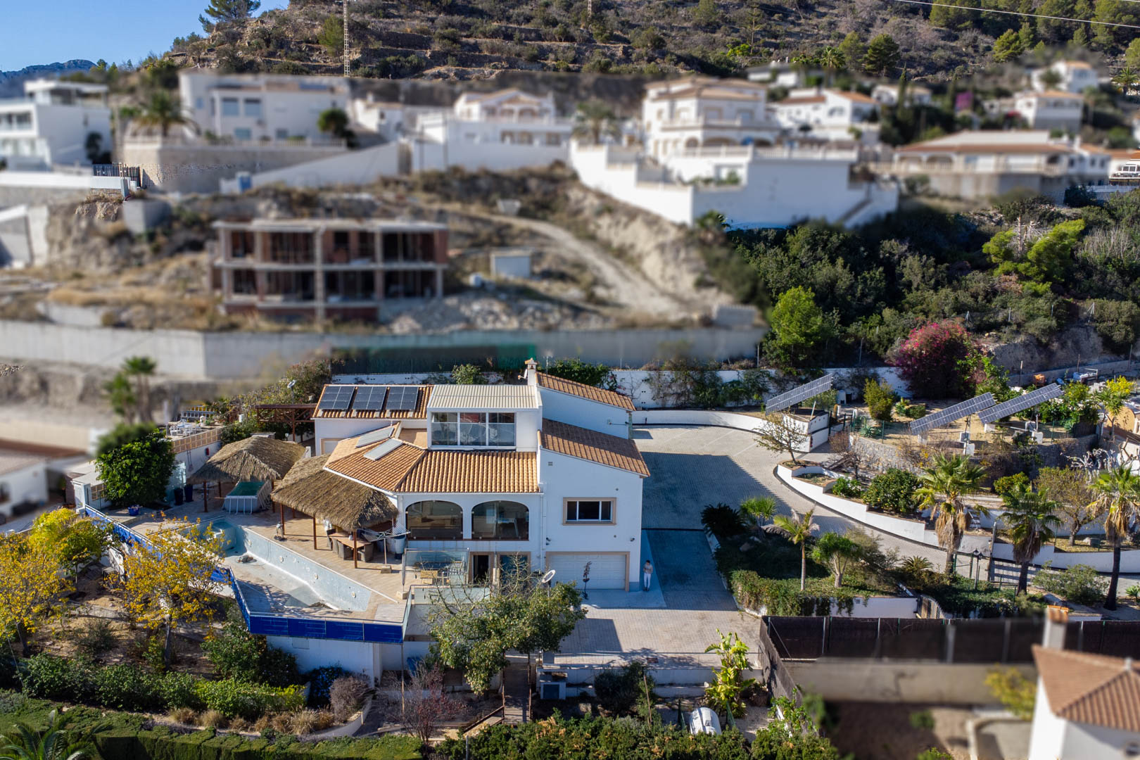 Vue aérienne de la propriété mettant en évidence les trois tours solaires motorisées, la vaste zone d'accès pavée et les terrasses avec pergolas en brande près de la piscine.