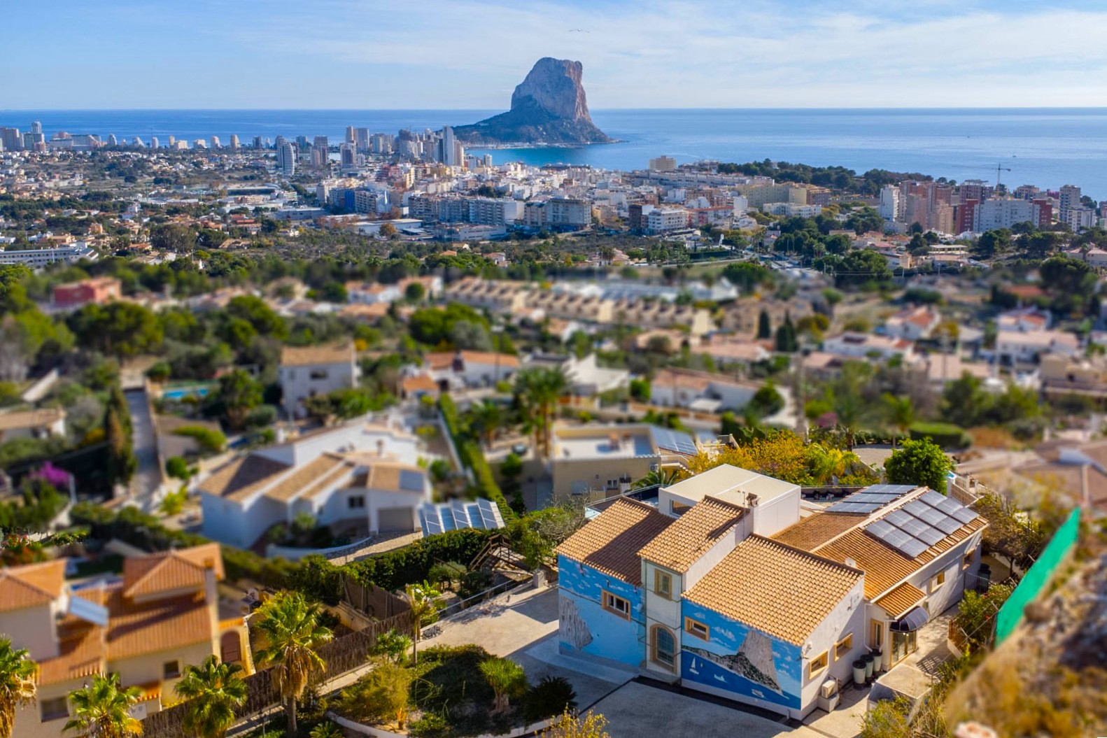 Vue aérienne de la villa avec ses panneaux solaires et sa fresque murale, surplombant le panorama de Calpe et le rocher d'Ifach face à la mer.