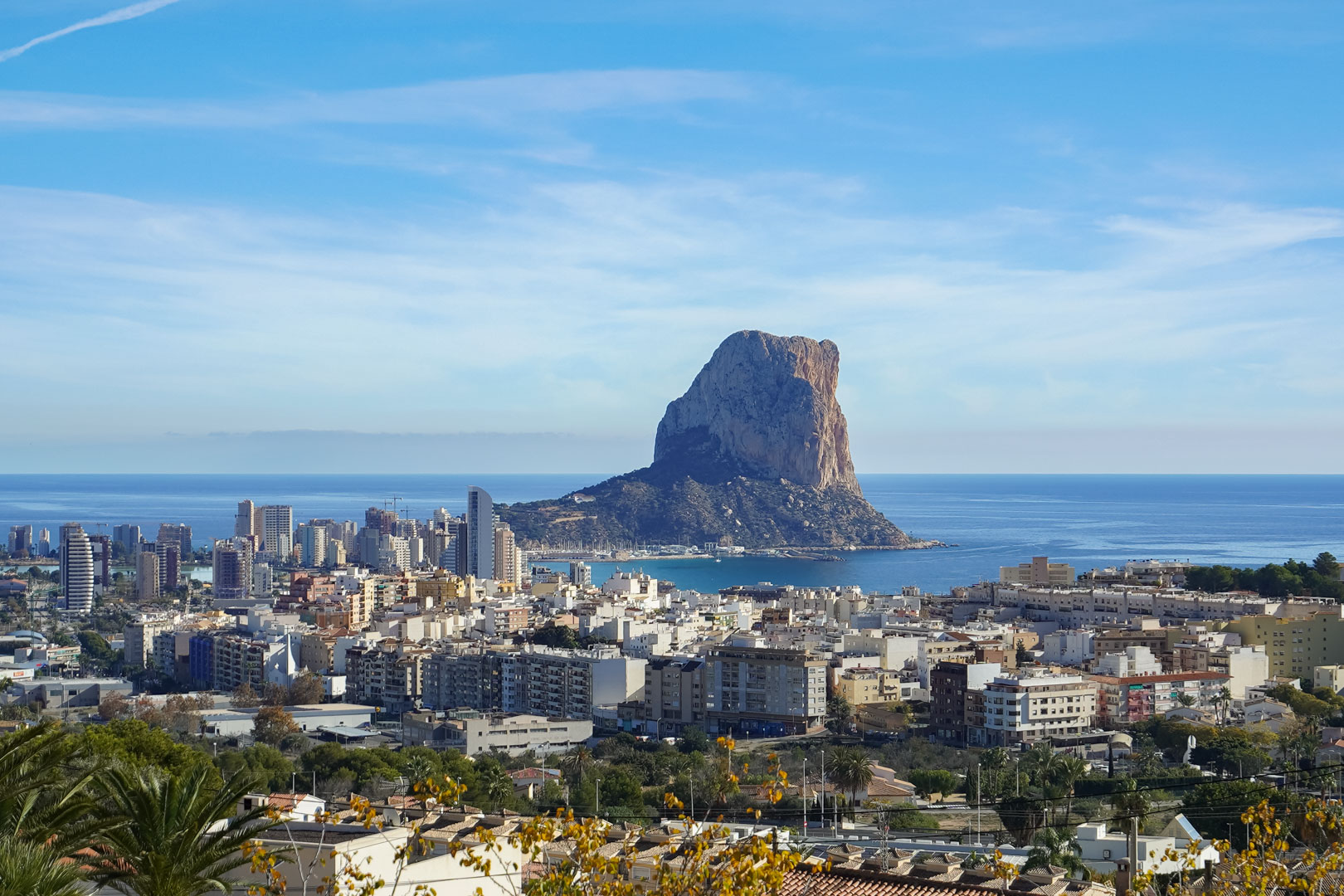Vue panoramique sur le Peñón de Ifach et la silhouette de Calpe depuis les hauteurs, révélant le littoral méditerranéen et le port de plaisance.