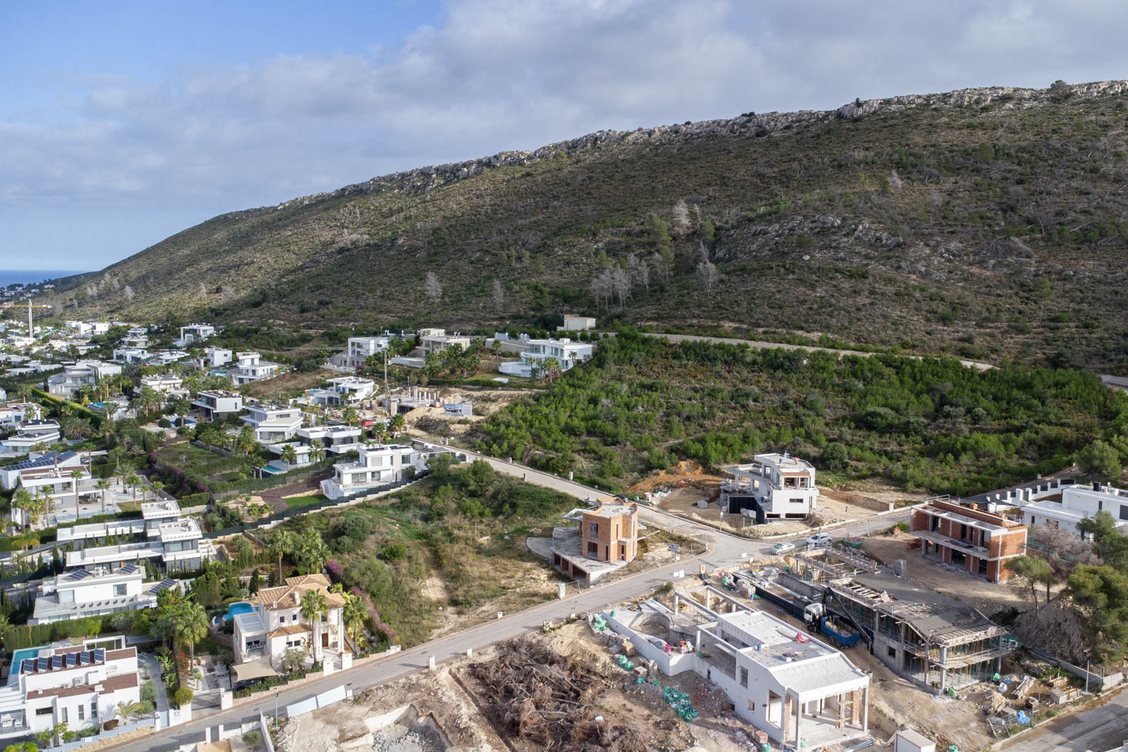 Vue aérienne du quartier résidentiel Monte Olímpico, présentant des parcelles urbanisées avec rues pavées, éclairage public et villas modernes au pied de la colline.