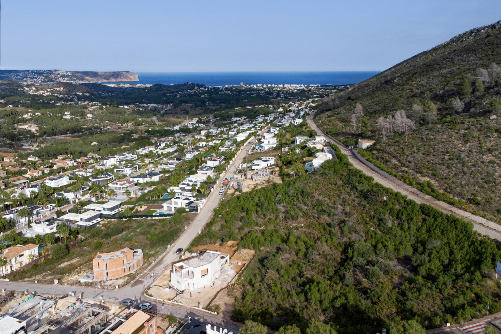 Vue aérienne du terrain à Monte Olímpico, Jávea, révélant une zone résidentielle moderne avec des vues panoramiques sur la mer Méditerranée et le Cabo de San Antonio.