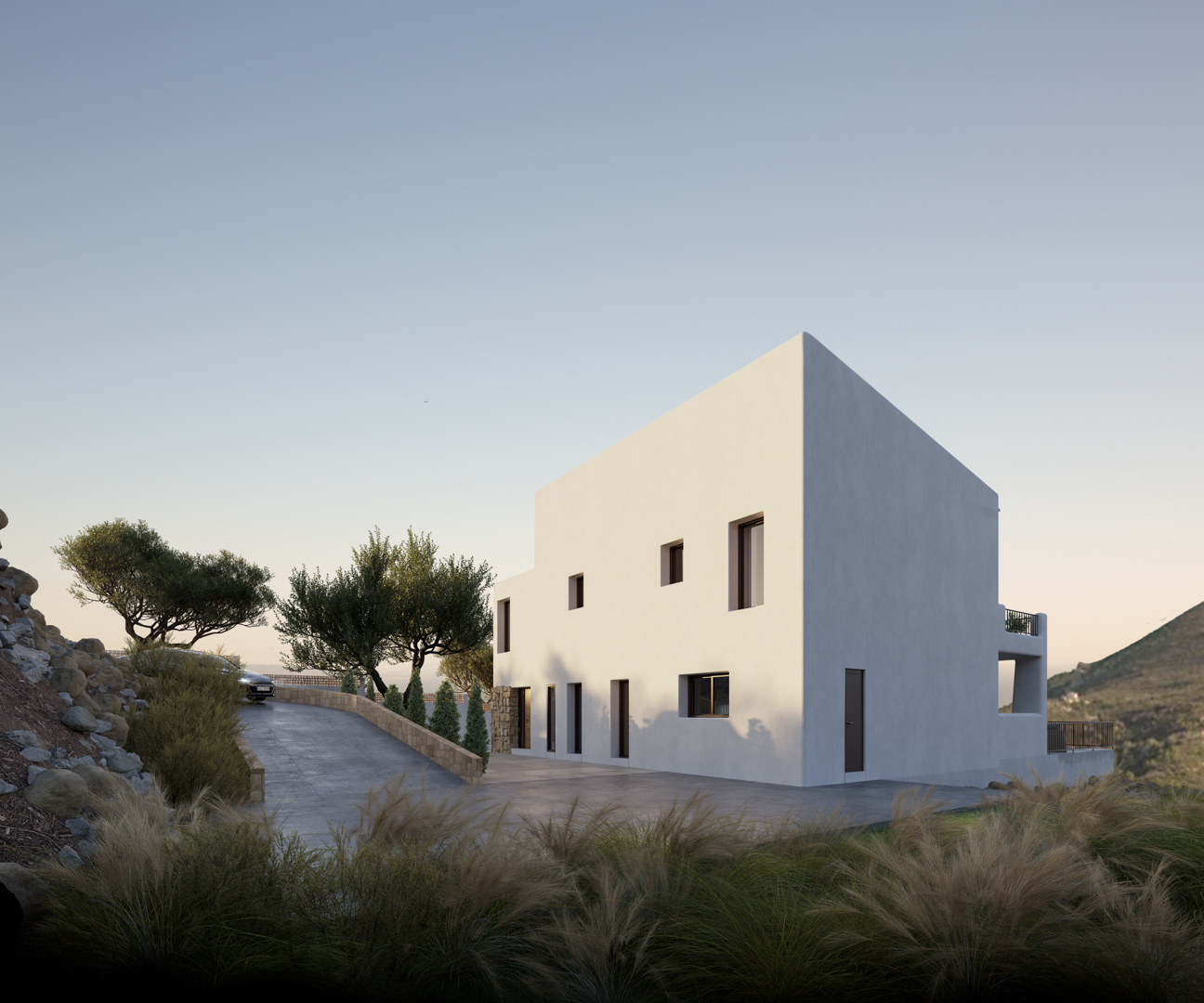 Vue extérieure de la villa de style ibizien avec façade blanche minimaliste, rampe d'accès pavée et murs en pierre naturelle intégrés au paysage d'Alcalalí.