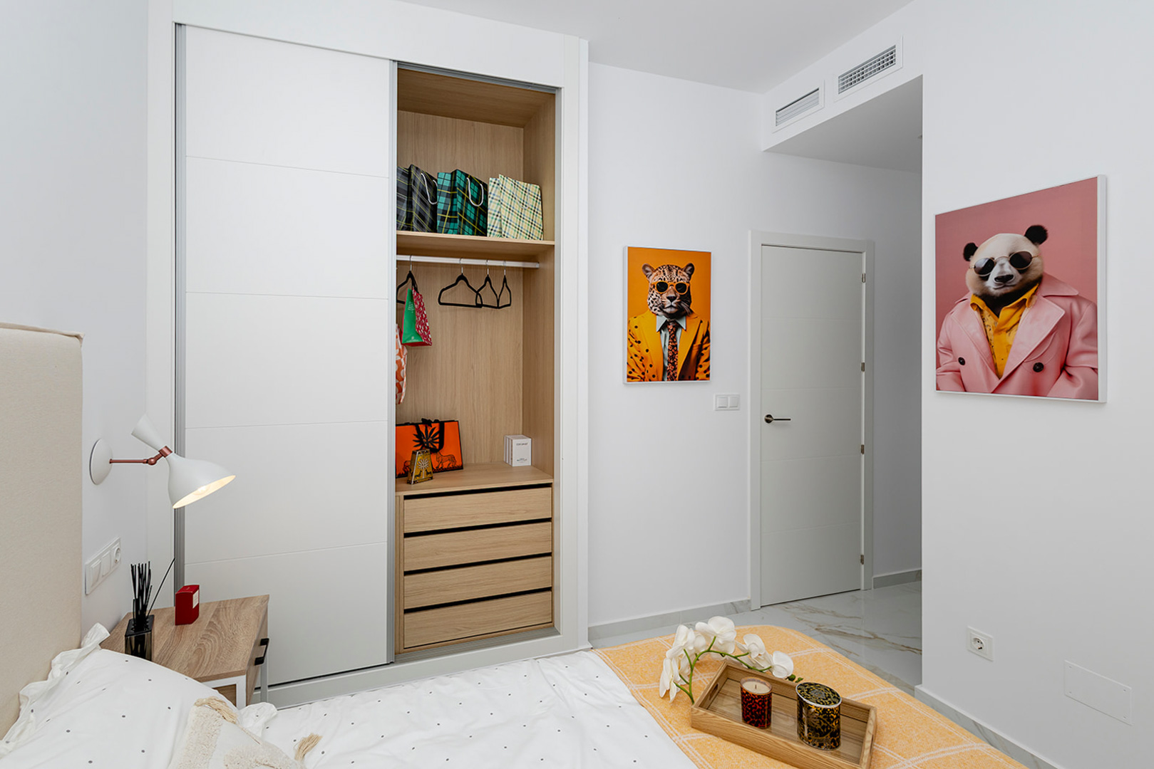 Chambre avec placard intégré à portes coulissantes blanches et intérieur en bois. Dispose d'un sol effet marbre et de la climatisation par conduits.