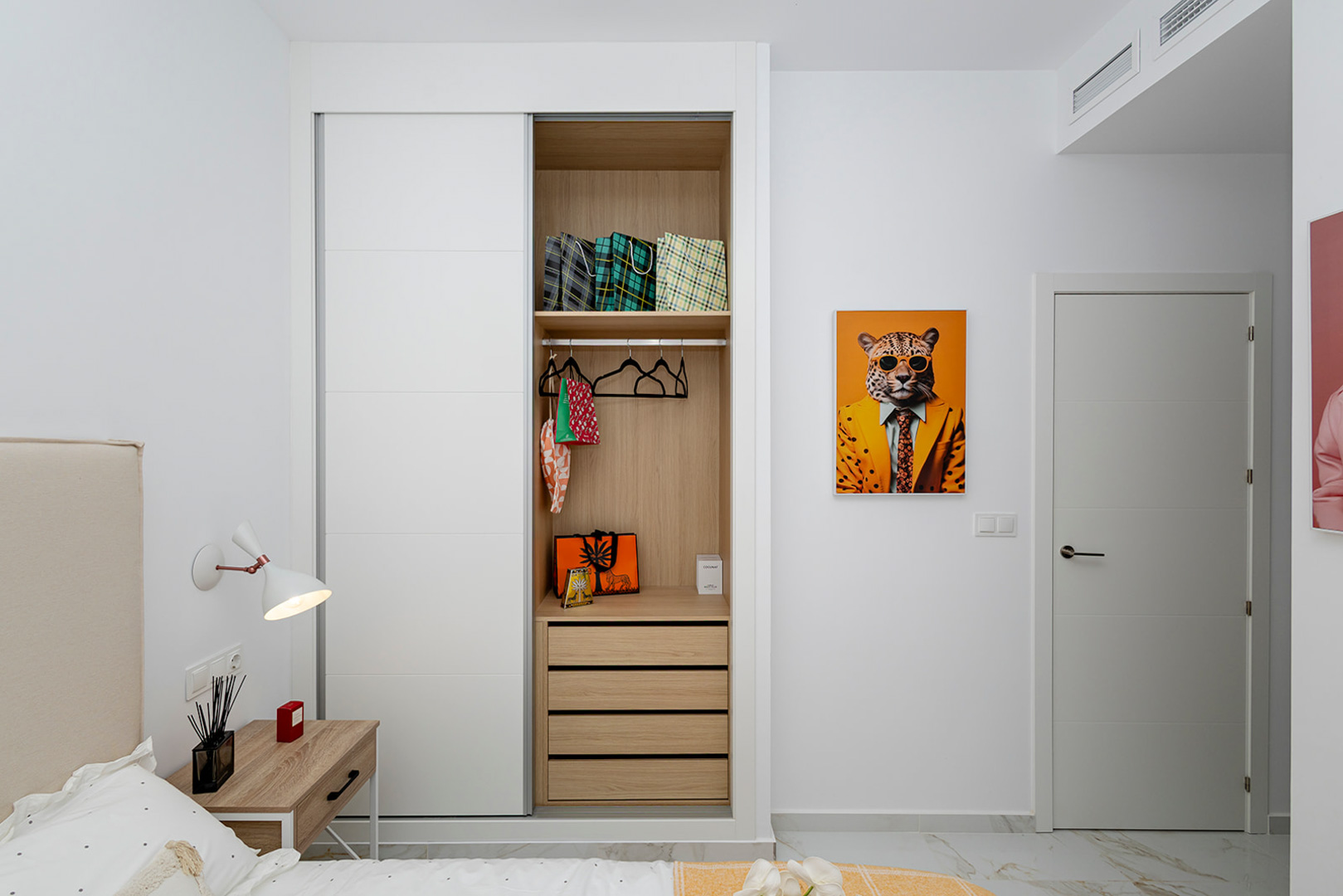 Chambre avec placard intégré à portes coulissantes blanches et intérieur en bois. Elle dispose d'un sol effet marbre et d'une climatisation par conduits.